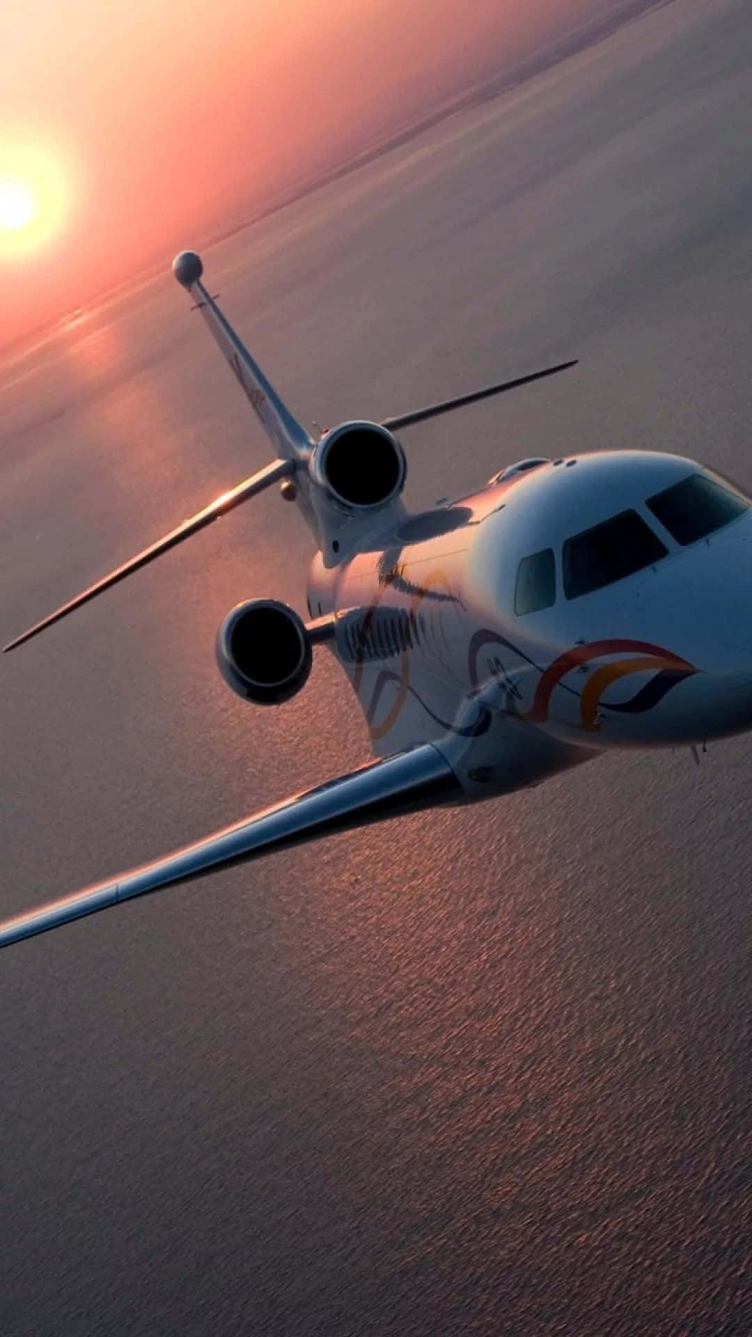 A Private Jet Flying Over The Ocean At Sunset Background