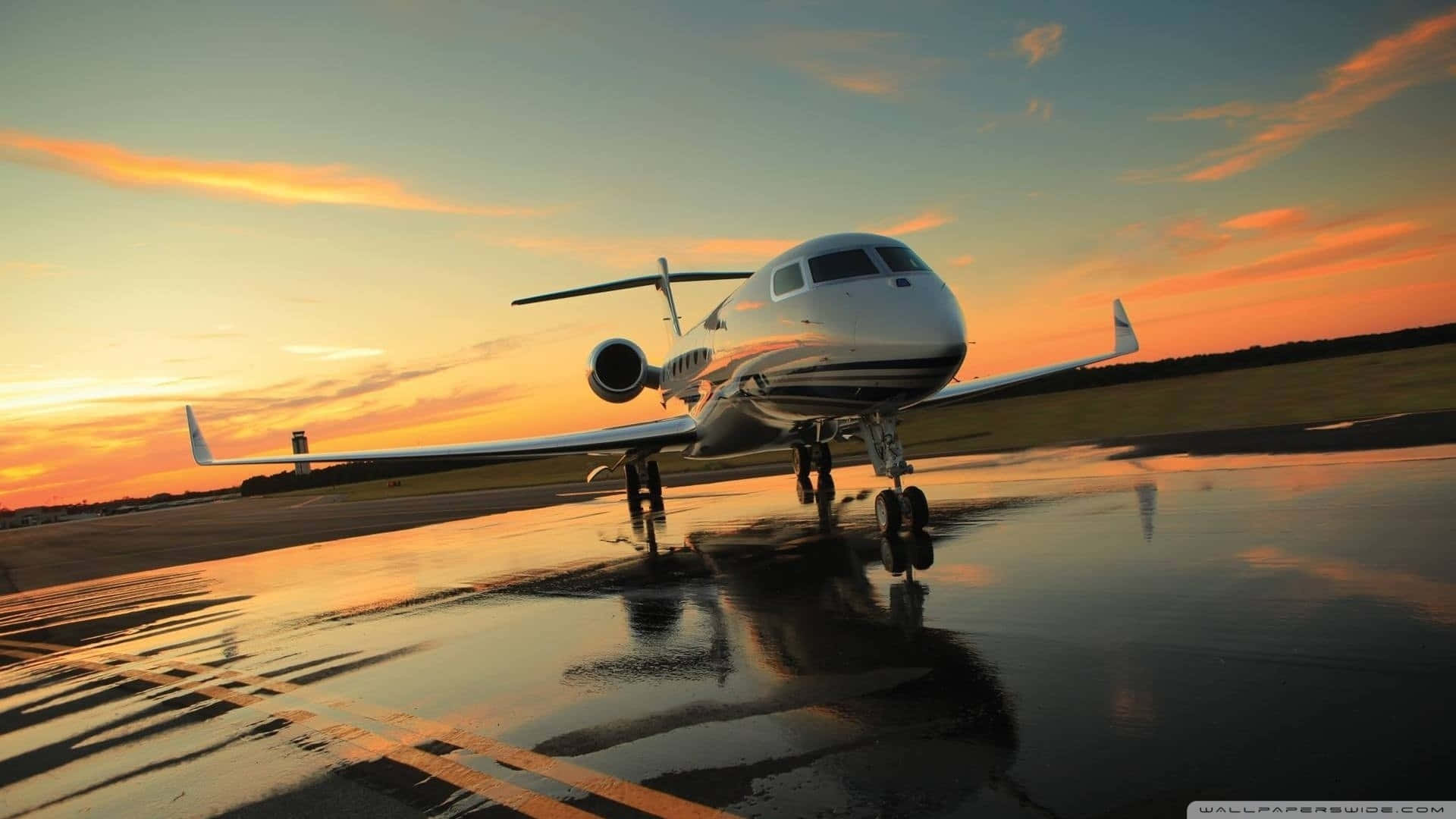 A Private Jet Sitting On The Runway At Sunset Background