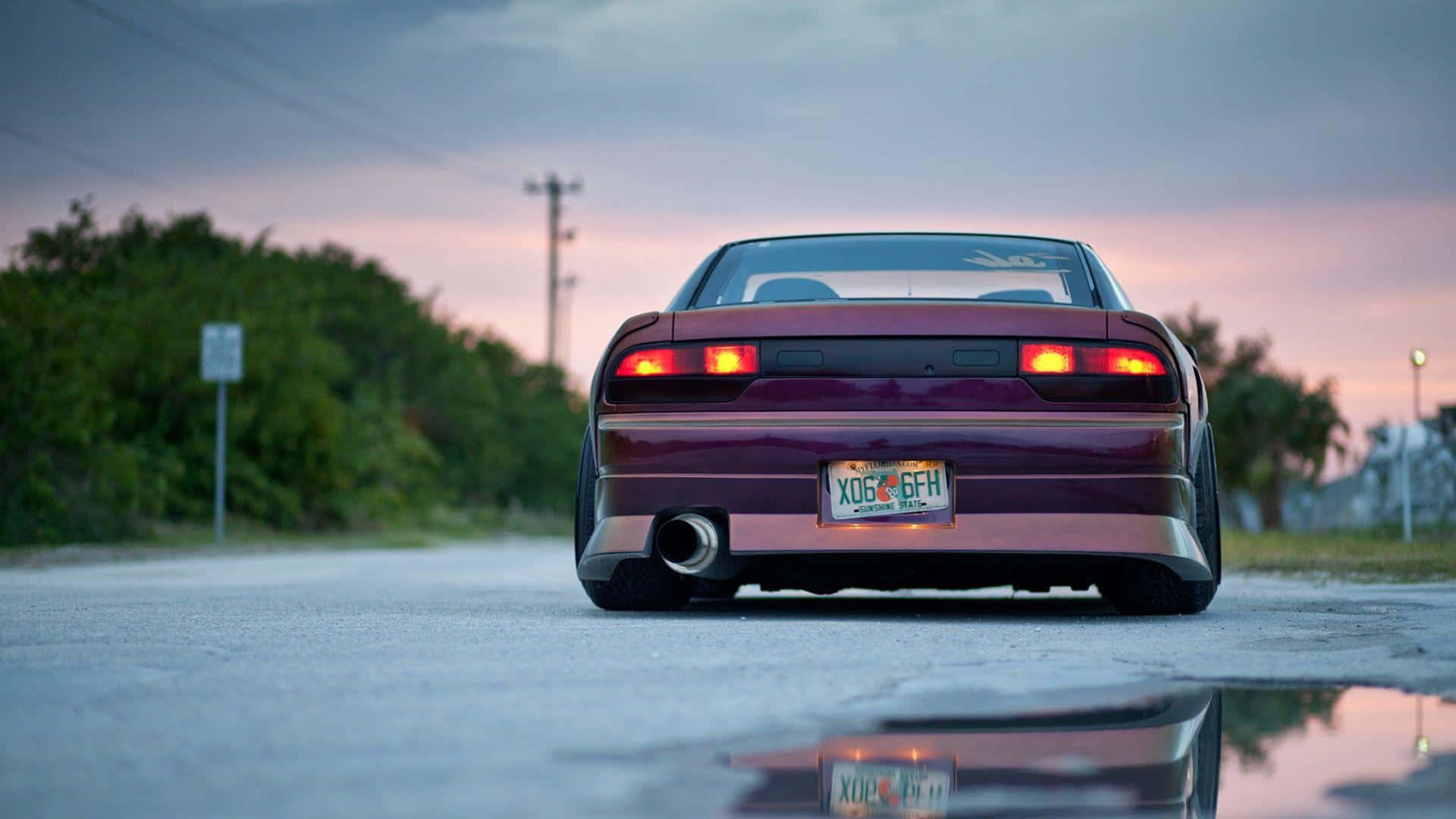 A Purple Car Is Parked On A Road At Sunset Background