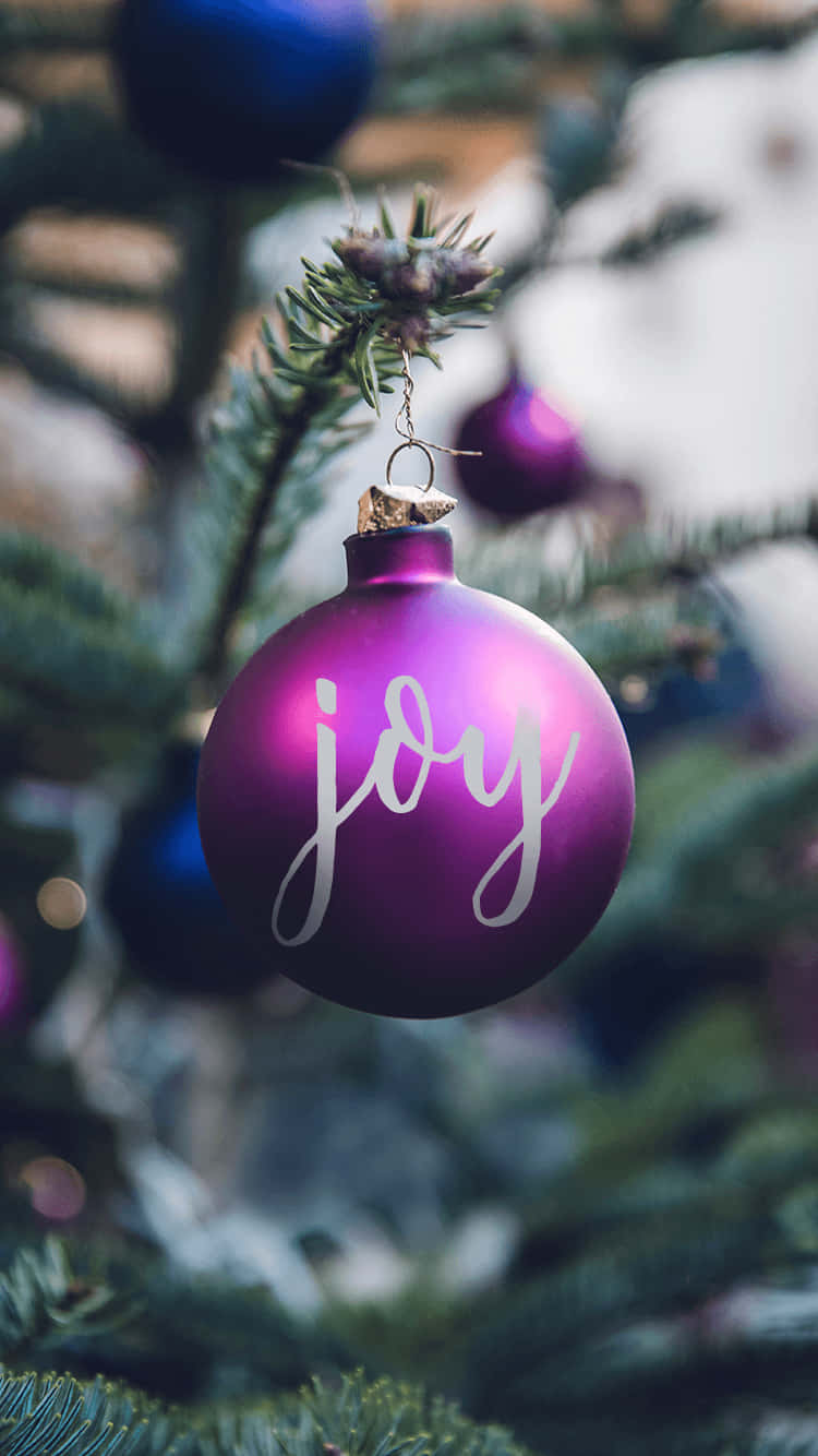 A Purple Christmas Ornament With The Word Joy Hanging On It Background