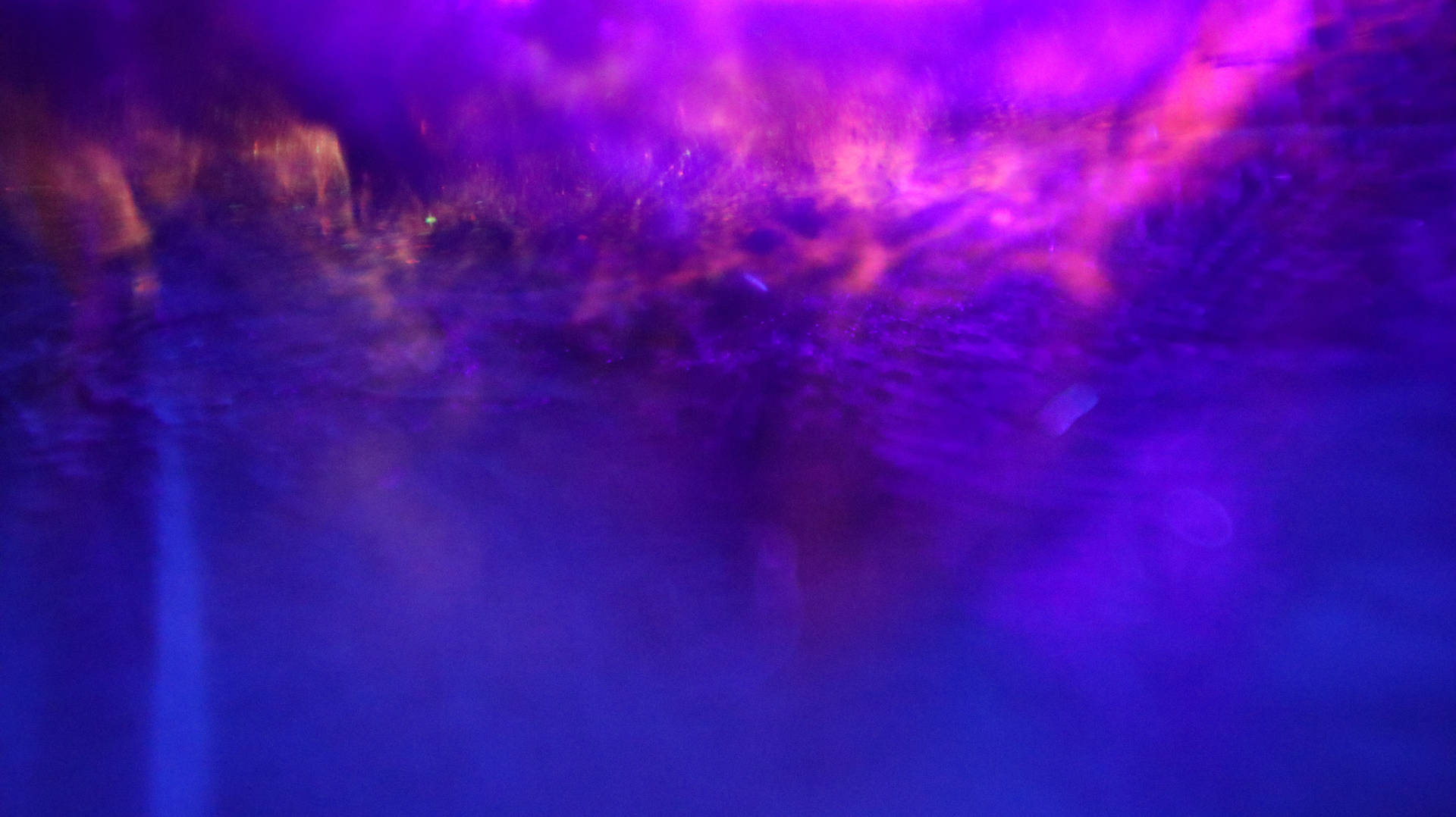 A Purple Light Is Shining On A Water Fountain Background