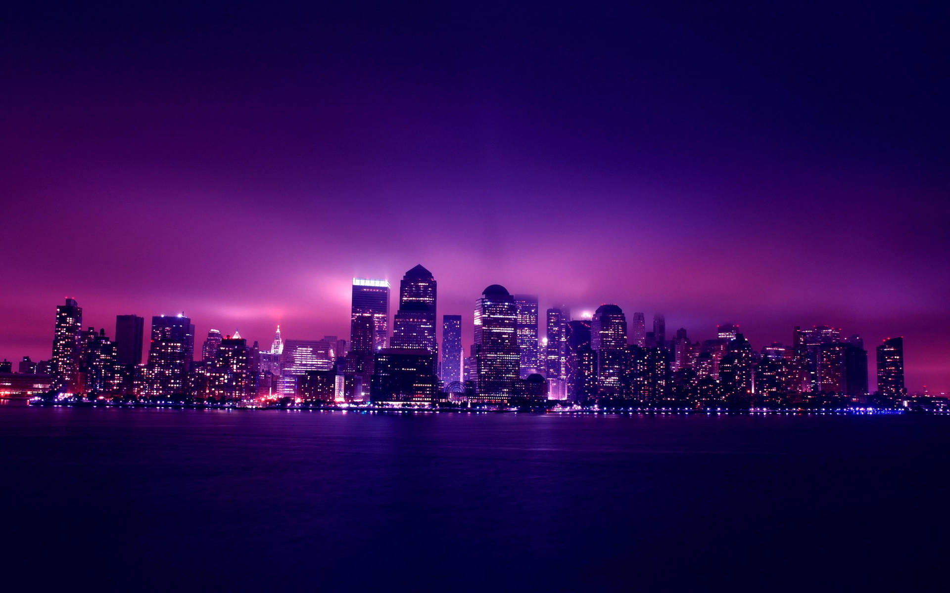 A Purple Skyline With Lights Over The Water Background