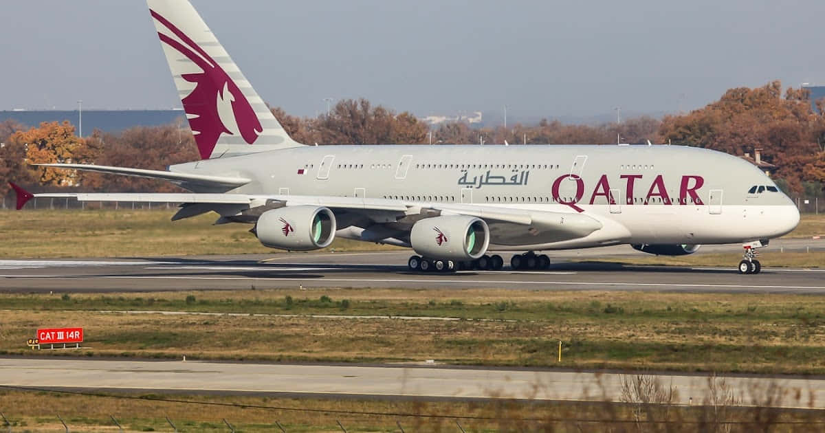 A Qatar Airways Airplane Is Taking Off From An Airport Background