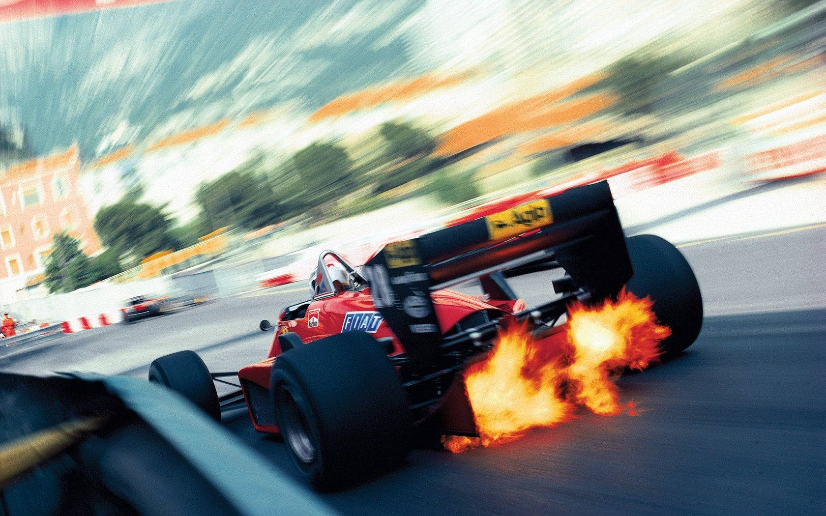 A Racing Car Is Driving Down A Street With Flames Background