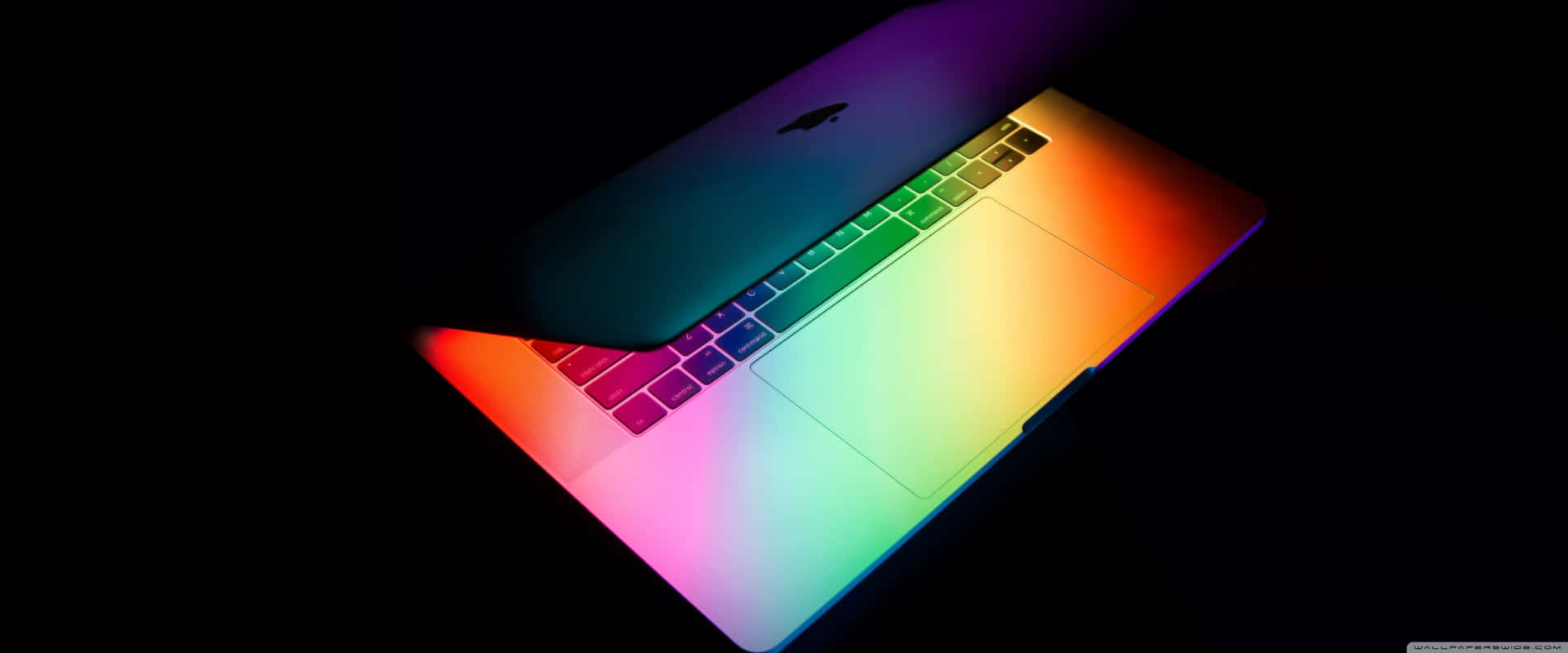 A Rainbow Colored Macbook Pro Is Shown In The Dark Background