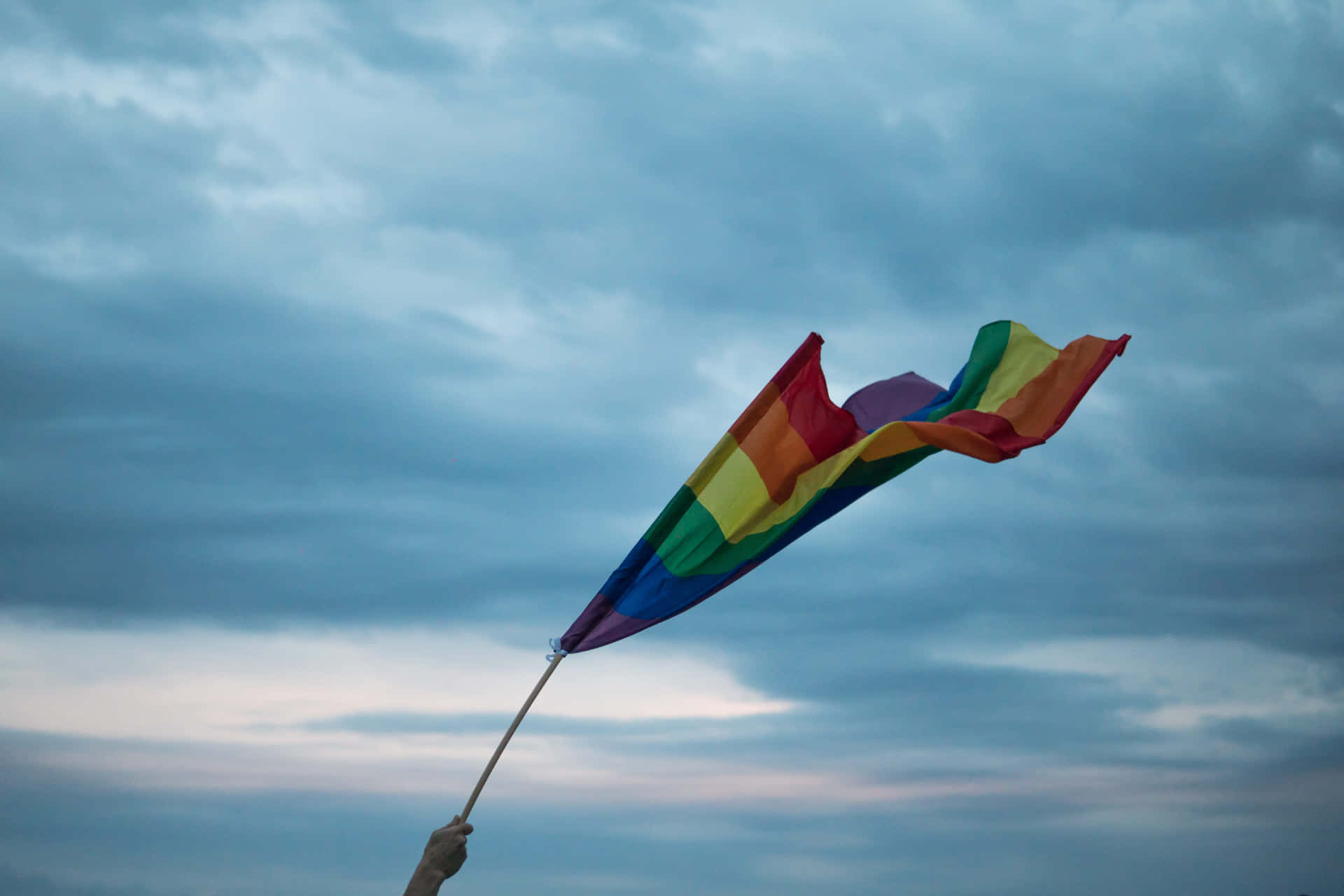 A Rainbow Flag Is Being Held Up By A Person