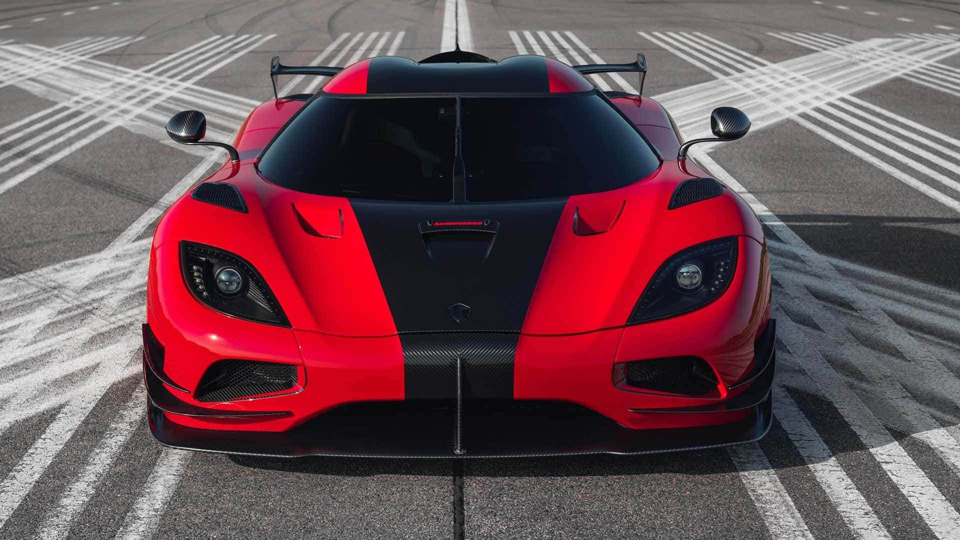 A Red And Black Sports Car Is Parked On An Asphalt Runway Background