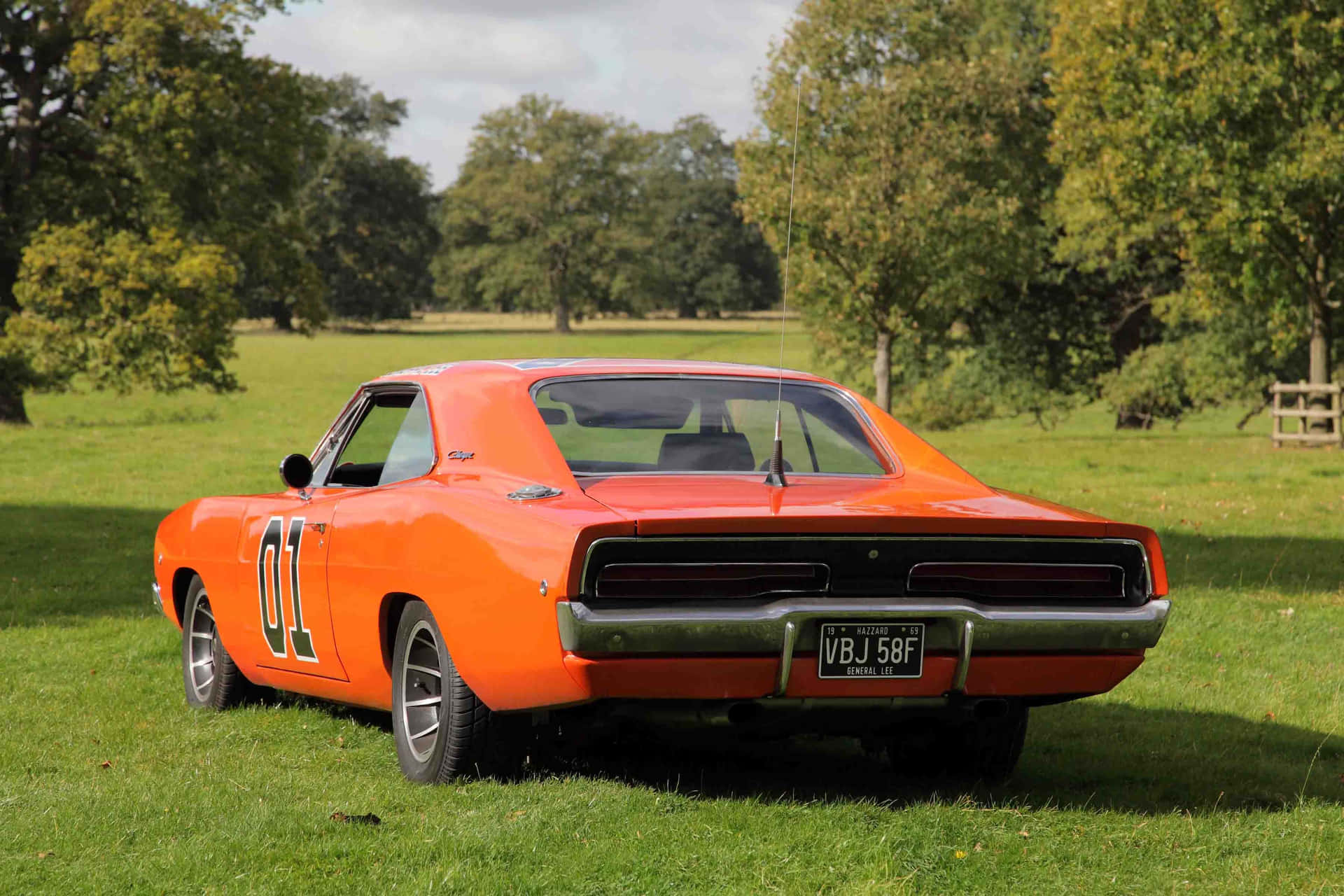 A Red And Orange Car Parked In A Field Background