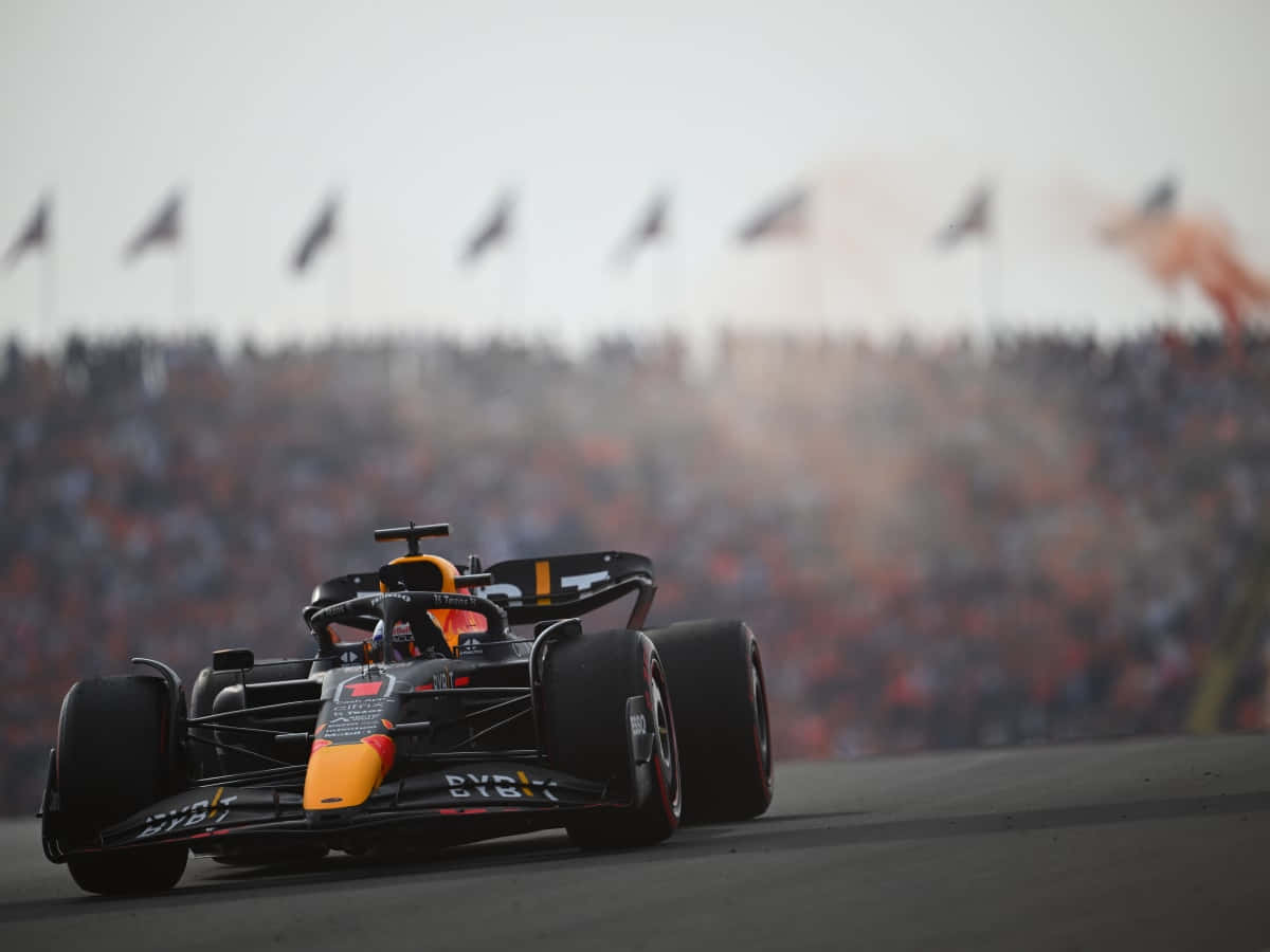 A Red Bull Racing Car Driving Down A Track Background