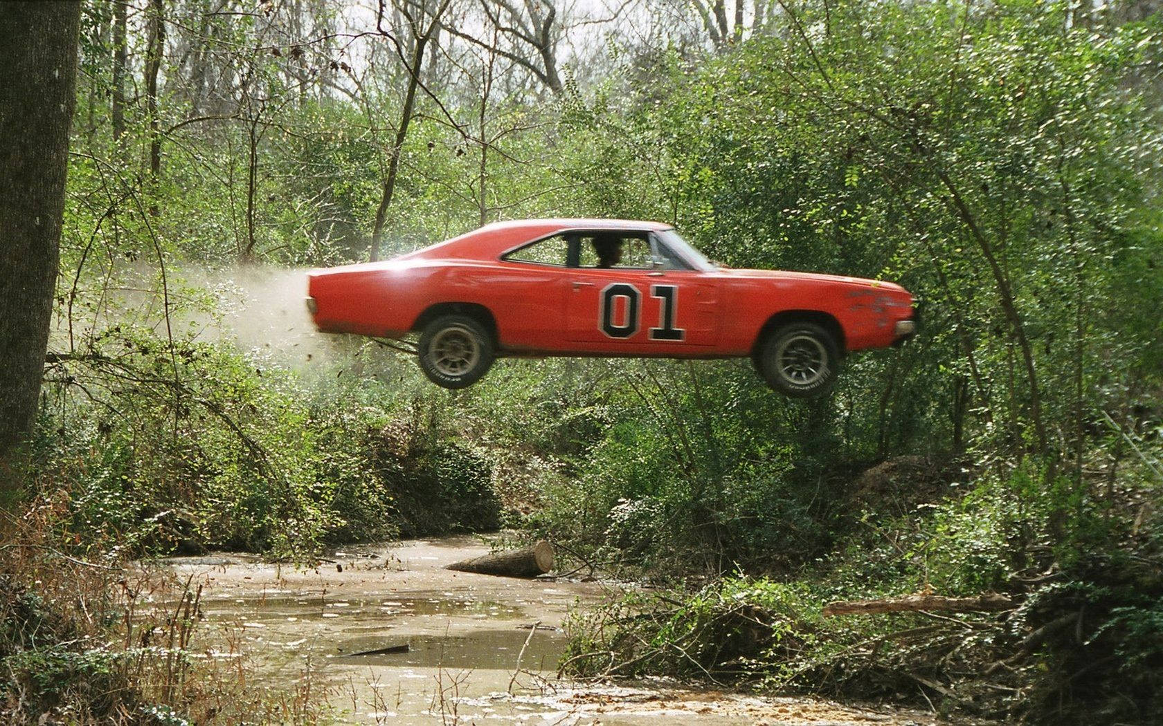 A Red Car Is Flying Over A Stream Background