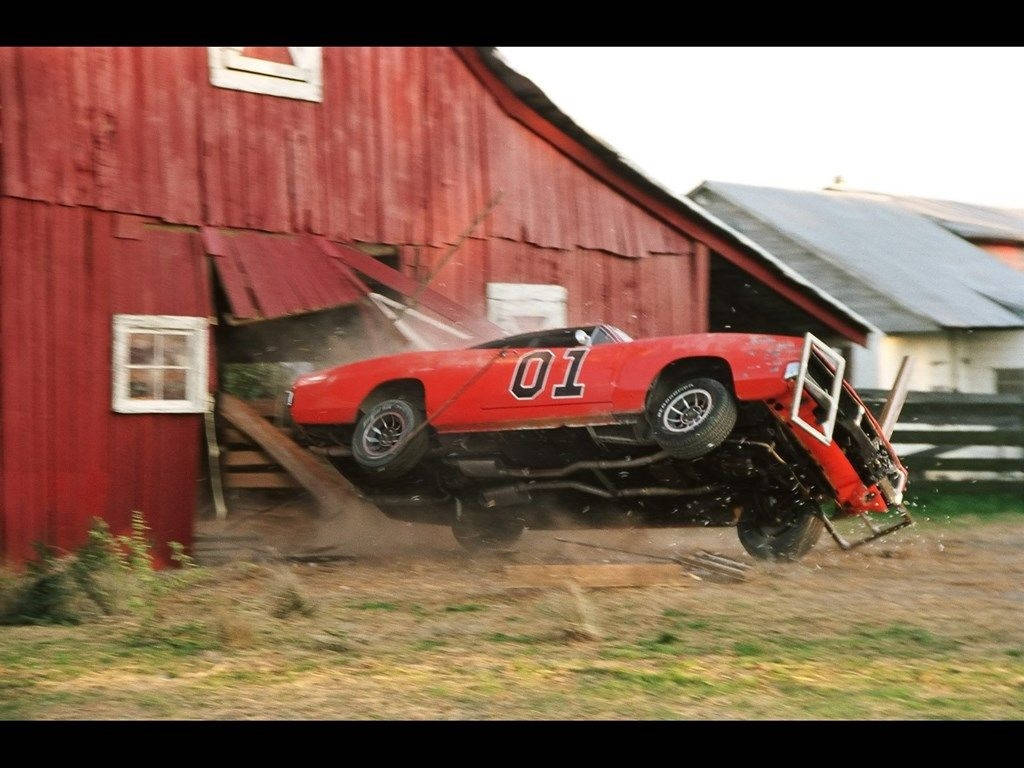 A Red Car Is Parked In Front Of A Barn