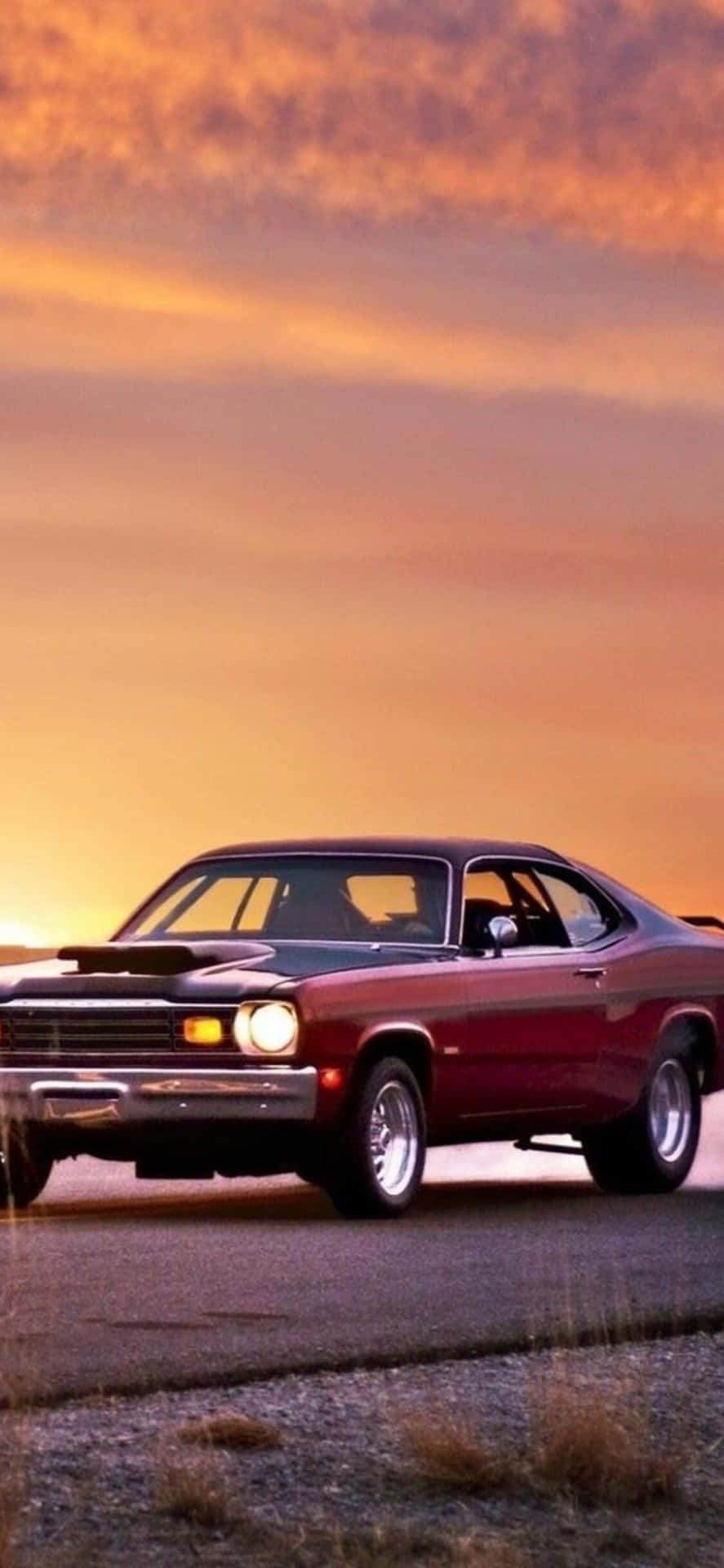 A Red Car Is Parked On A Road At Sunset Background