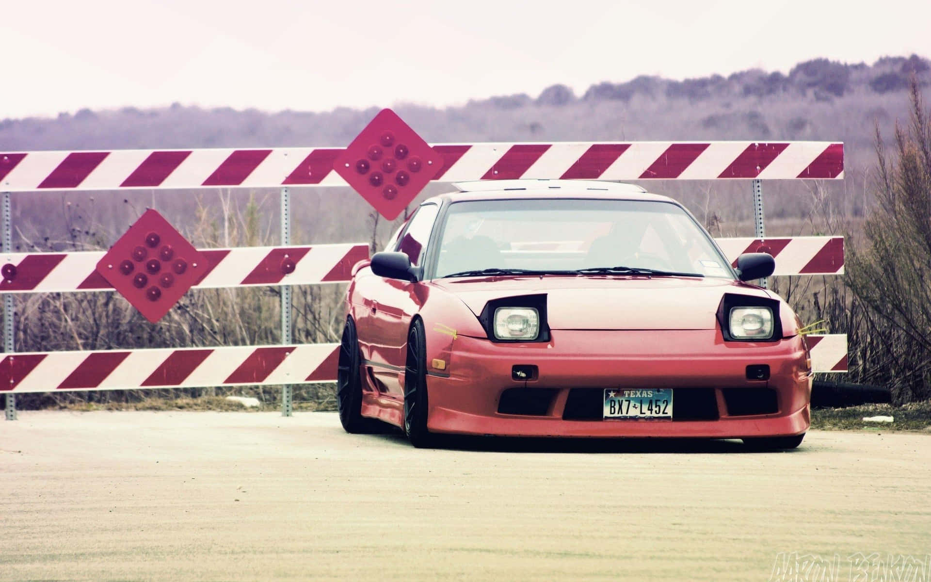 A Red Car Parked In Front Of A Fence Background