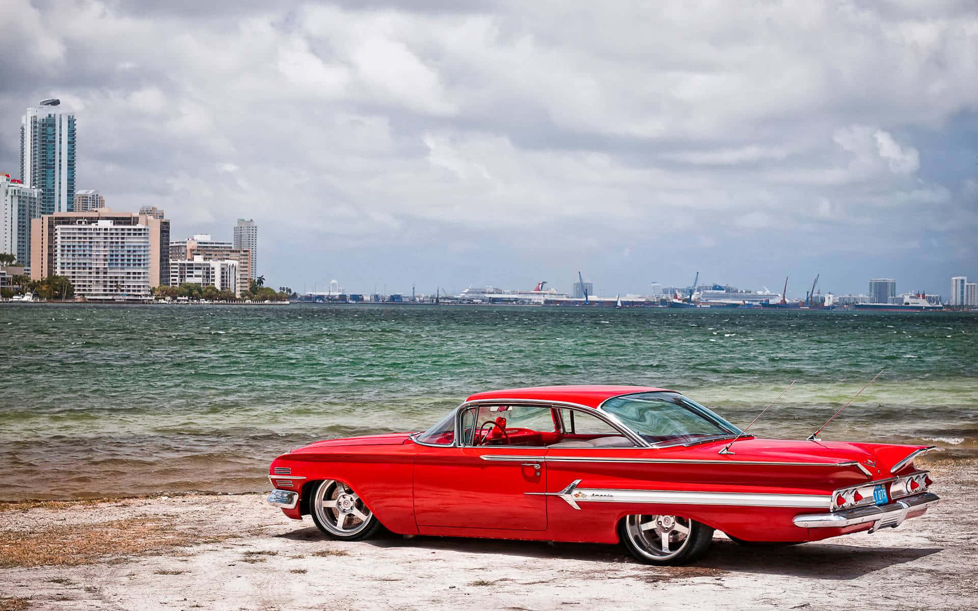 A Red Car Parked On The Beach Background