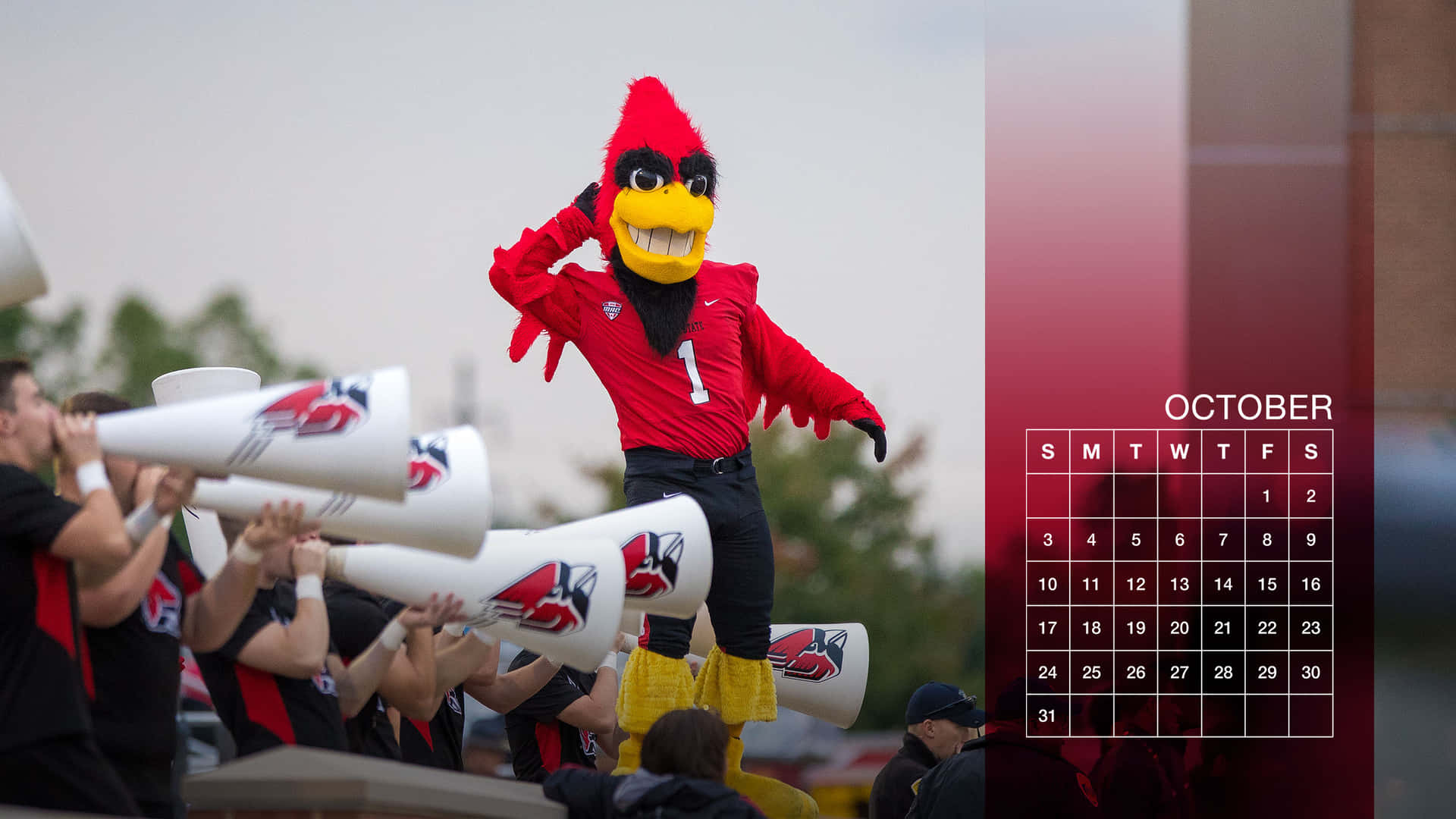 A Red Cardinal Mascot Is Holding A Horn Background