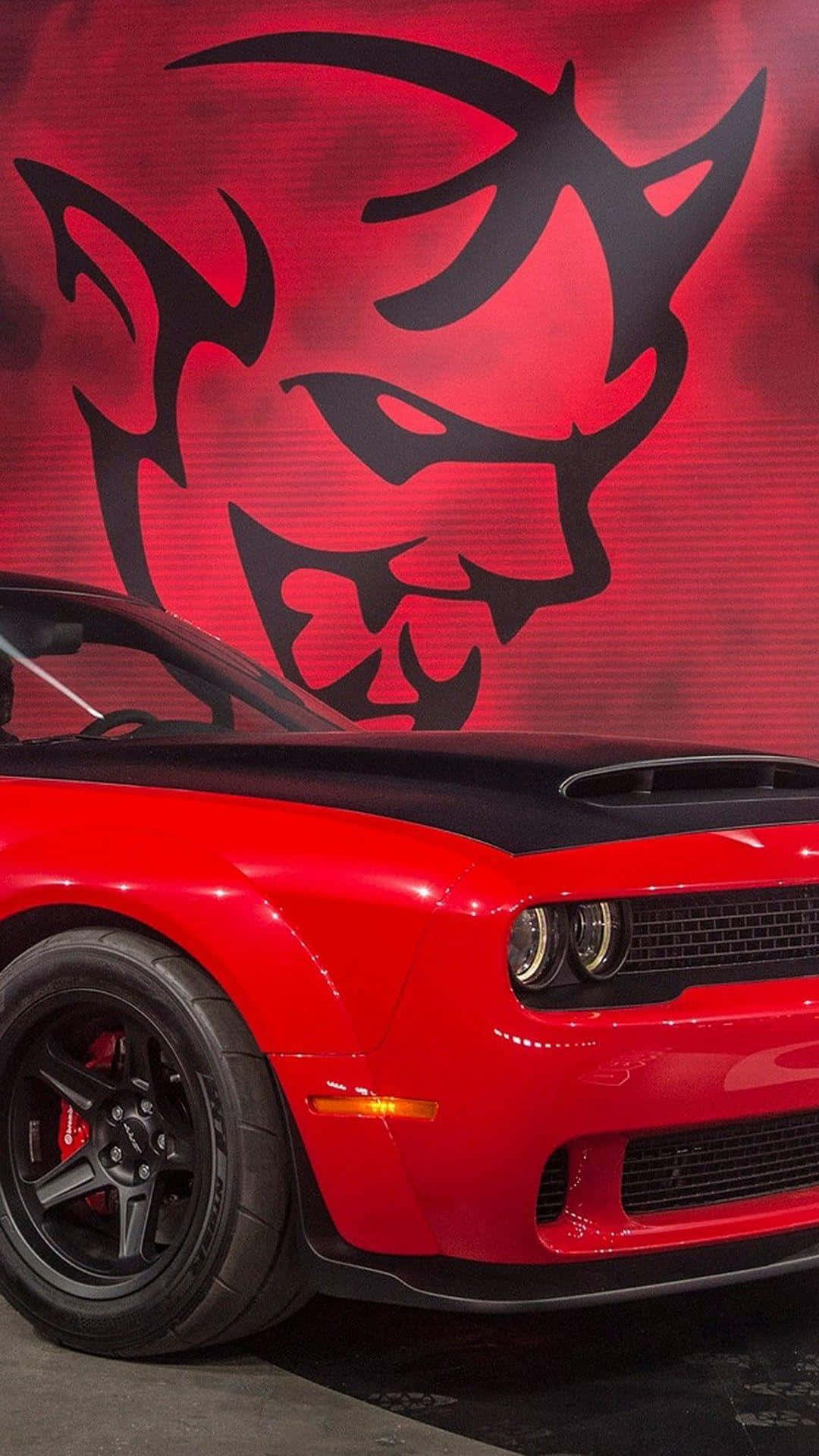 A Red Dodge Challenger Is Parked In Front Of A Devil Mural Background