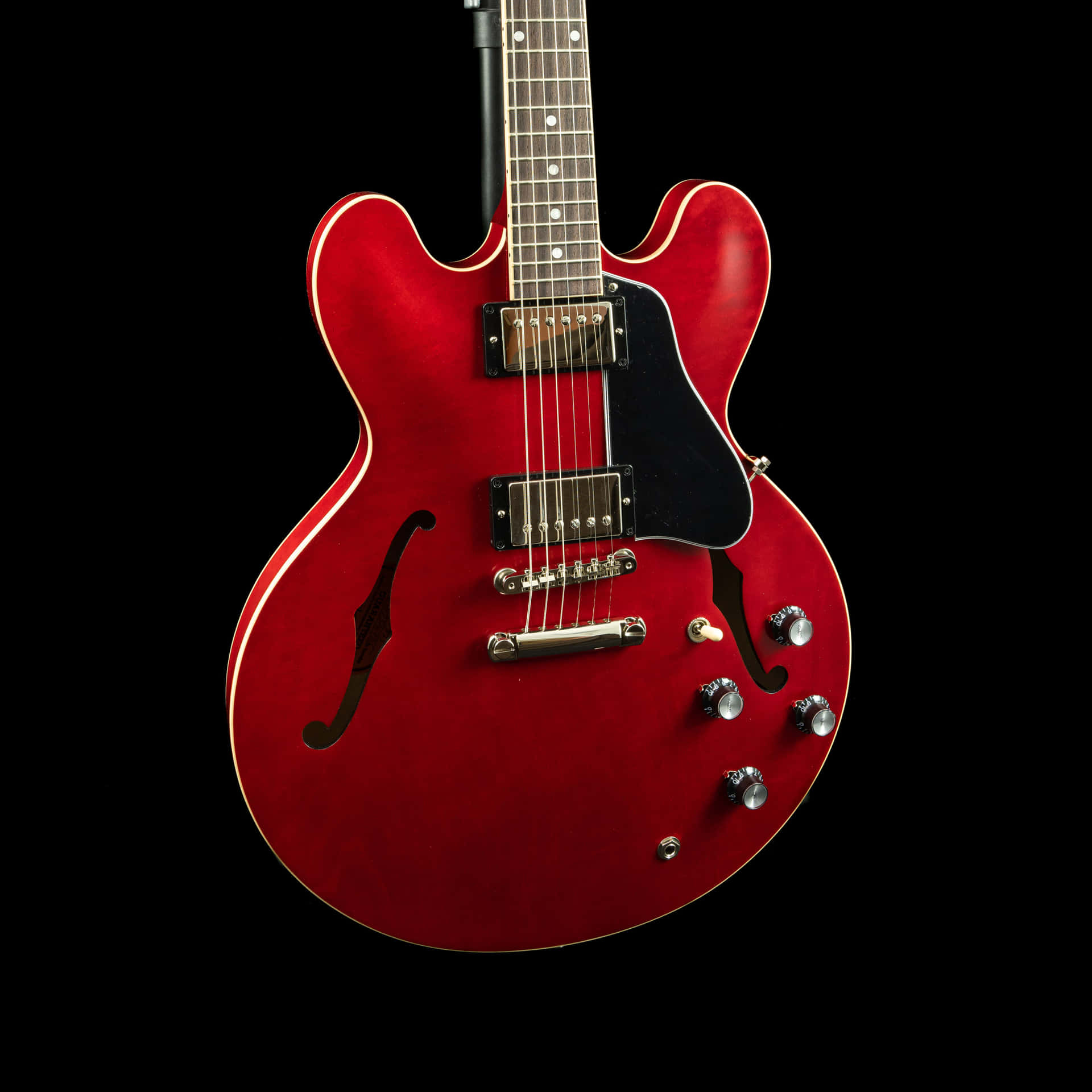 A Red Electric Guitar Is Shown Against A Black Background Background