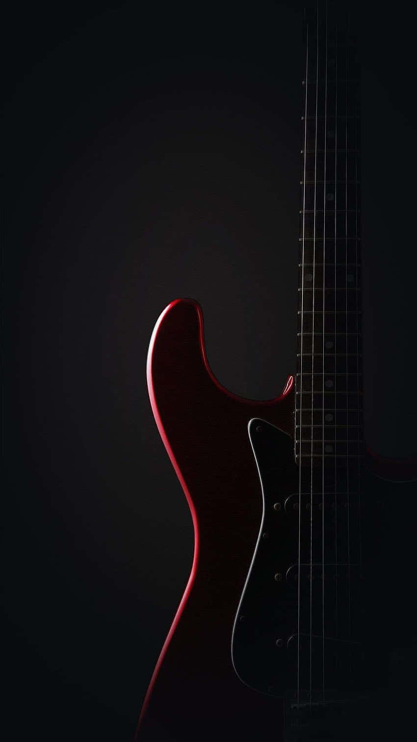 A Red Electric Guitar Is Shown Against A Black Background