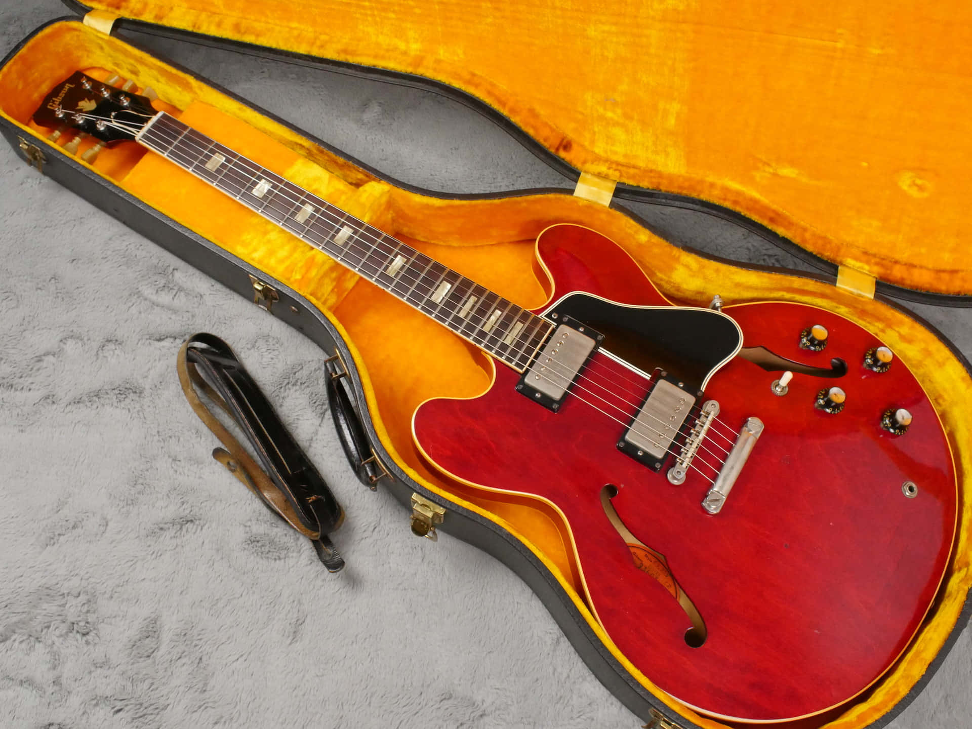 A Red Guitar Is Sitting In A Case With A Cord Background