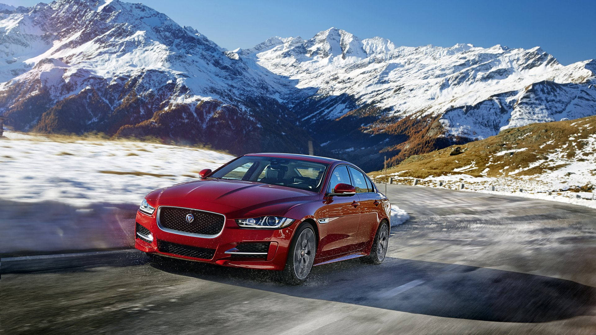 “a Red Jaguar Car Speeding Through A Mountain Range.” Background