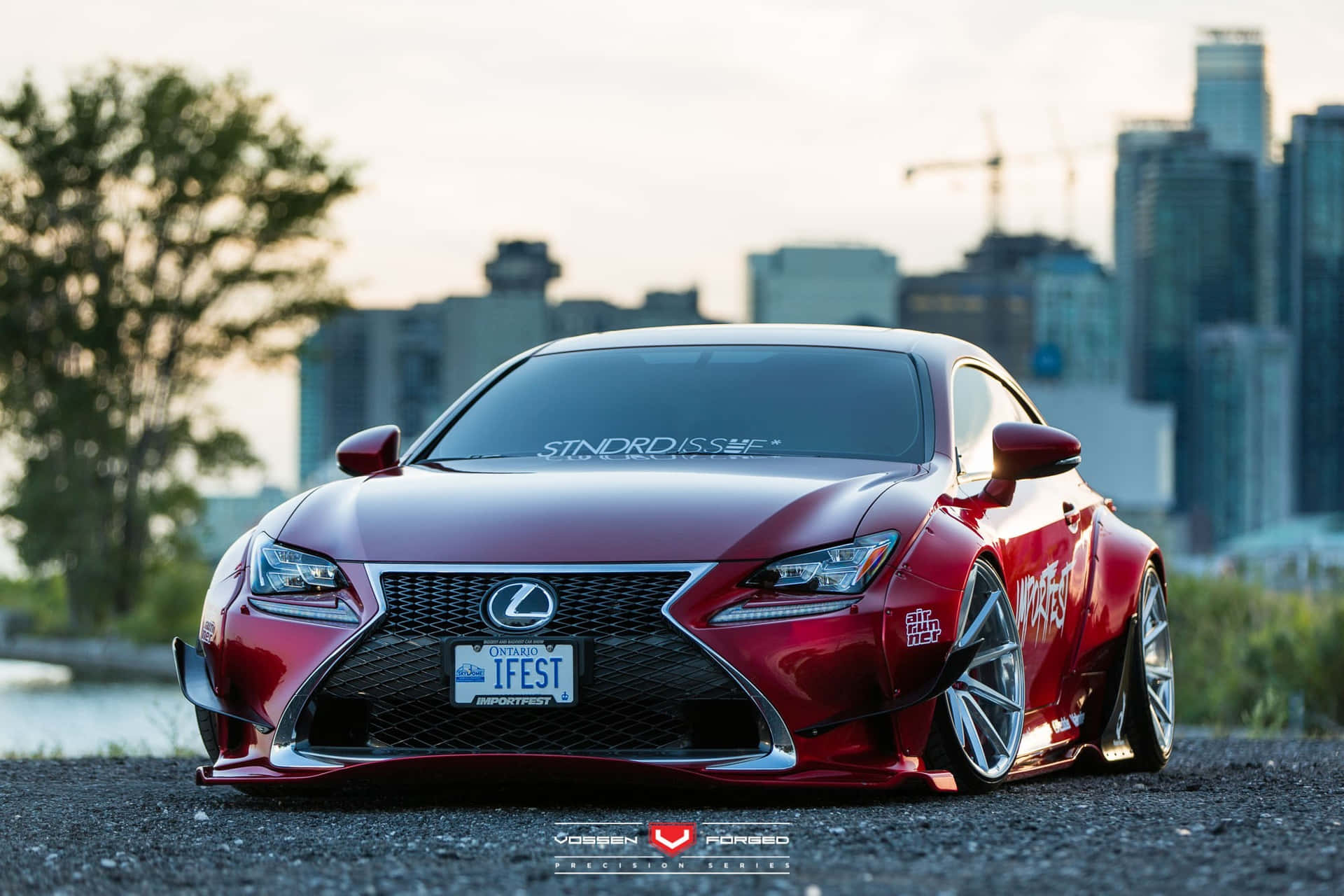 A Red Lexus Rc F Sport Parked In Front Of A City Background
