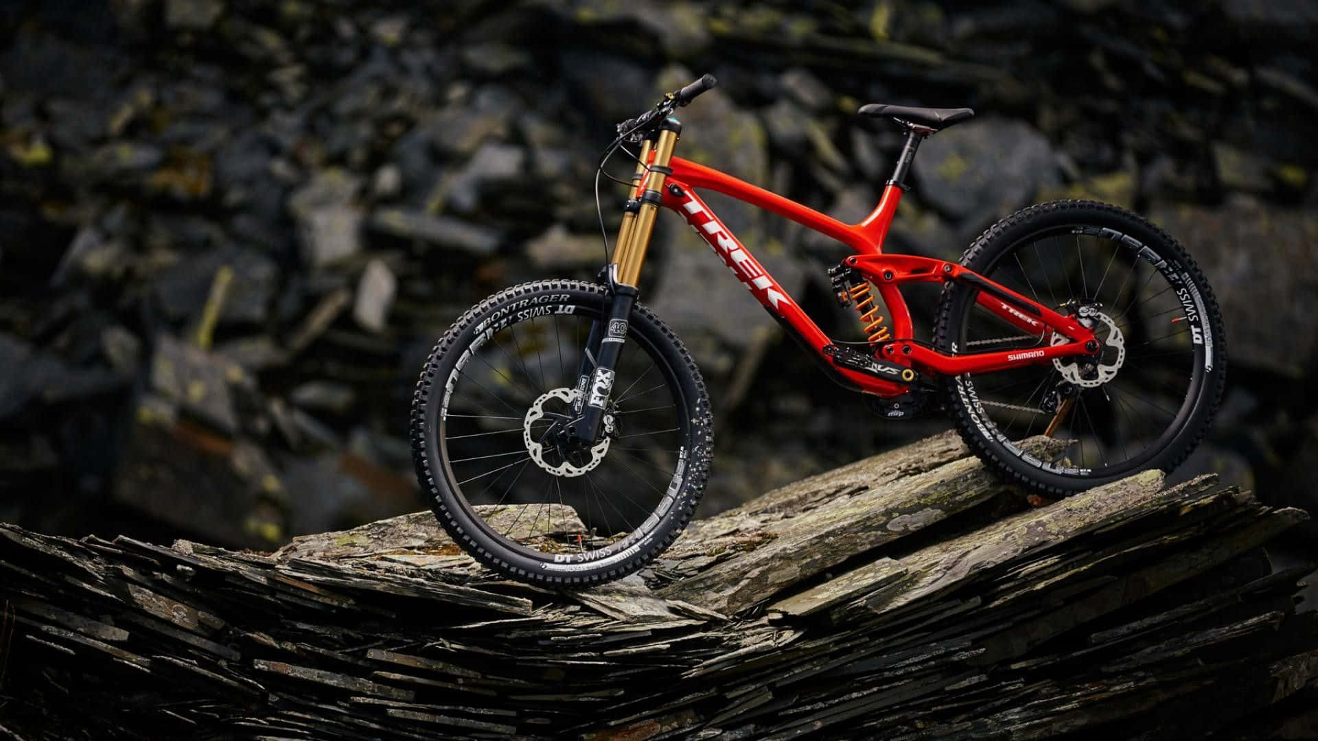 A Red Mountain Bike Is Sitting On Top Of Rocks Background