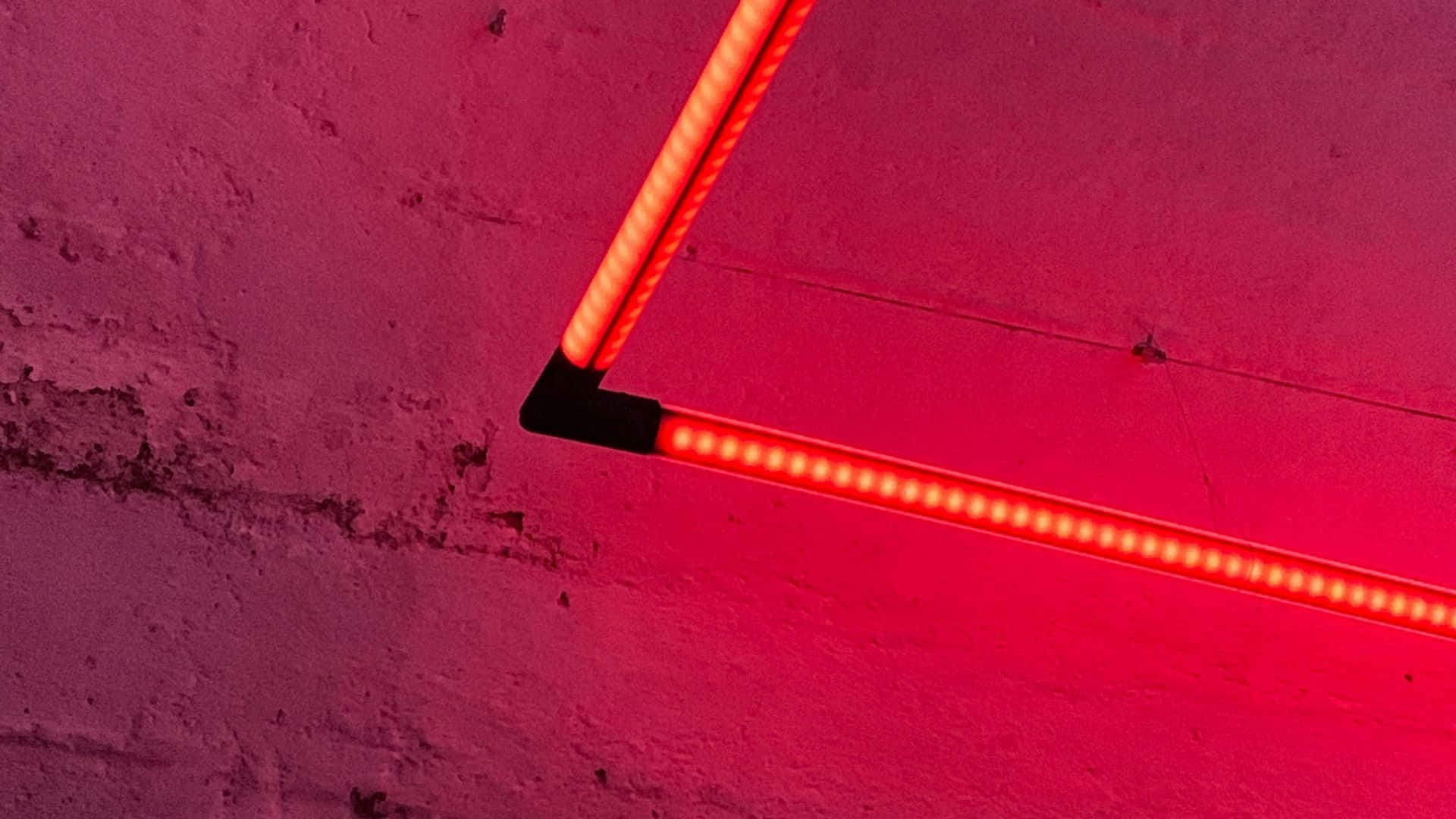 A Red Neon Light Is Hanging On A Wall Background
