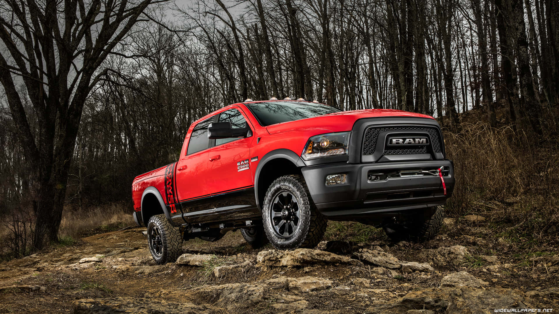 A Red Ram Truck Driving On A Rocky Trail Background