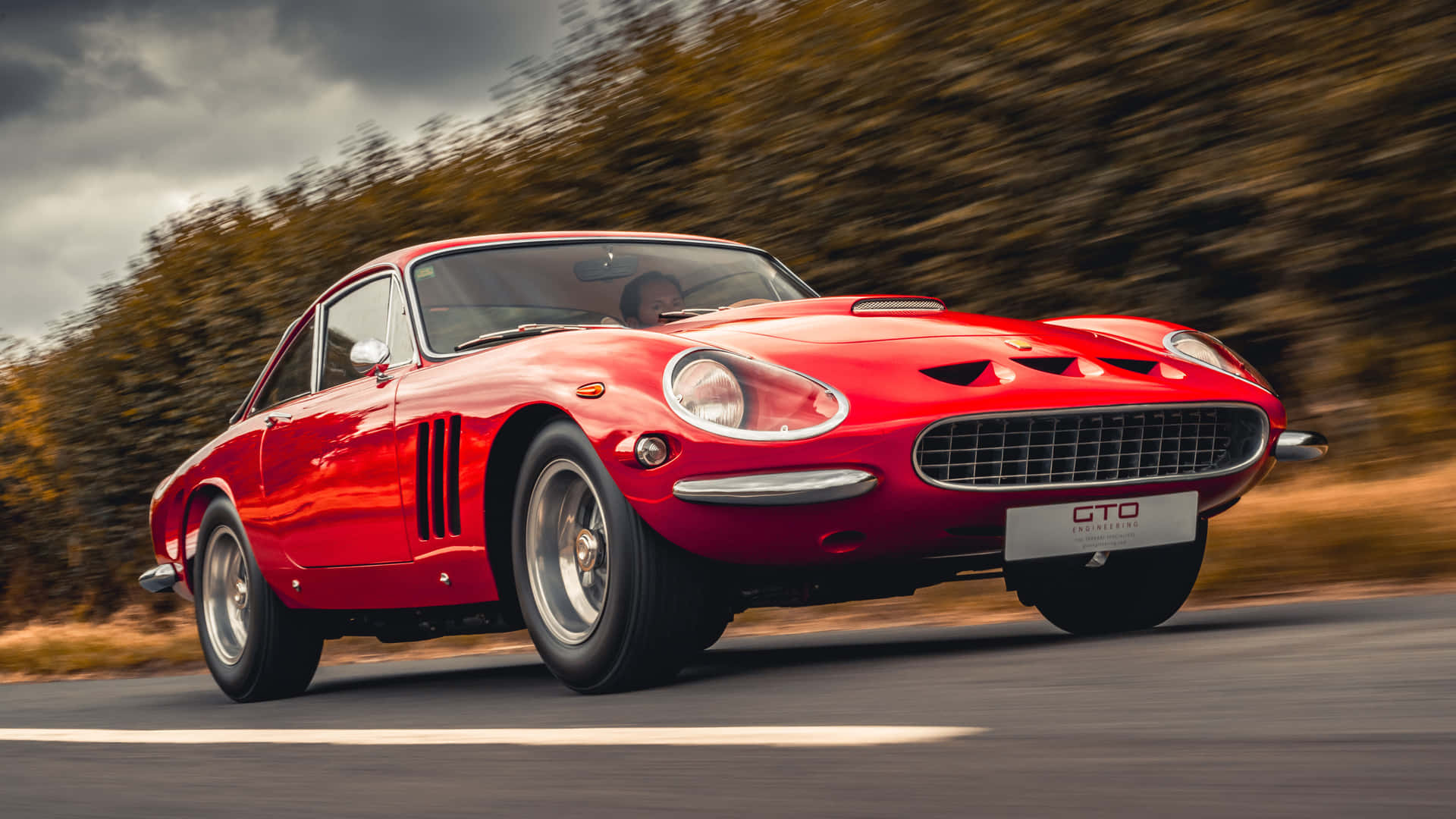 A Red Sports Car Driving Down A Road