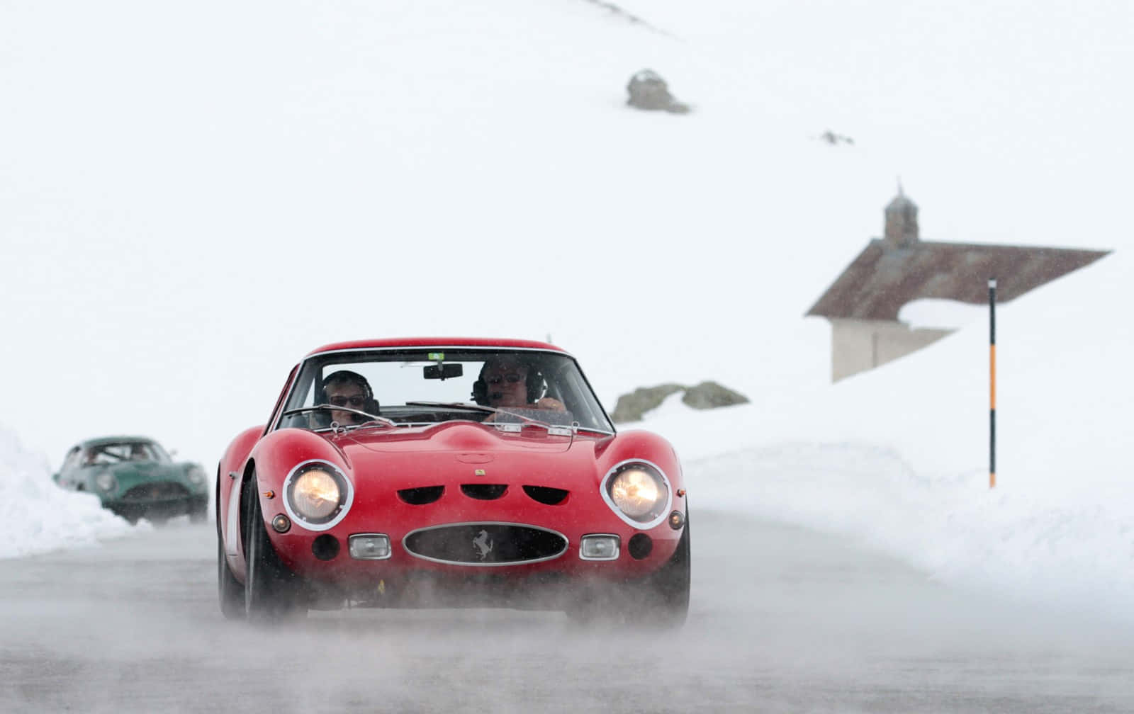 A Red Sports Car Driving Down A Snowy Road Background