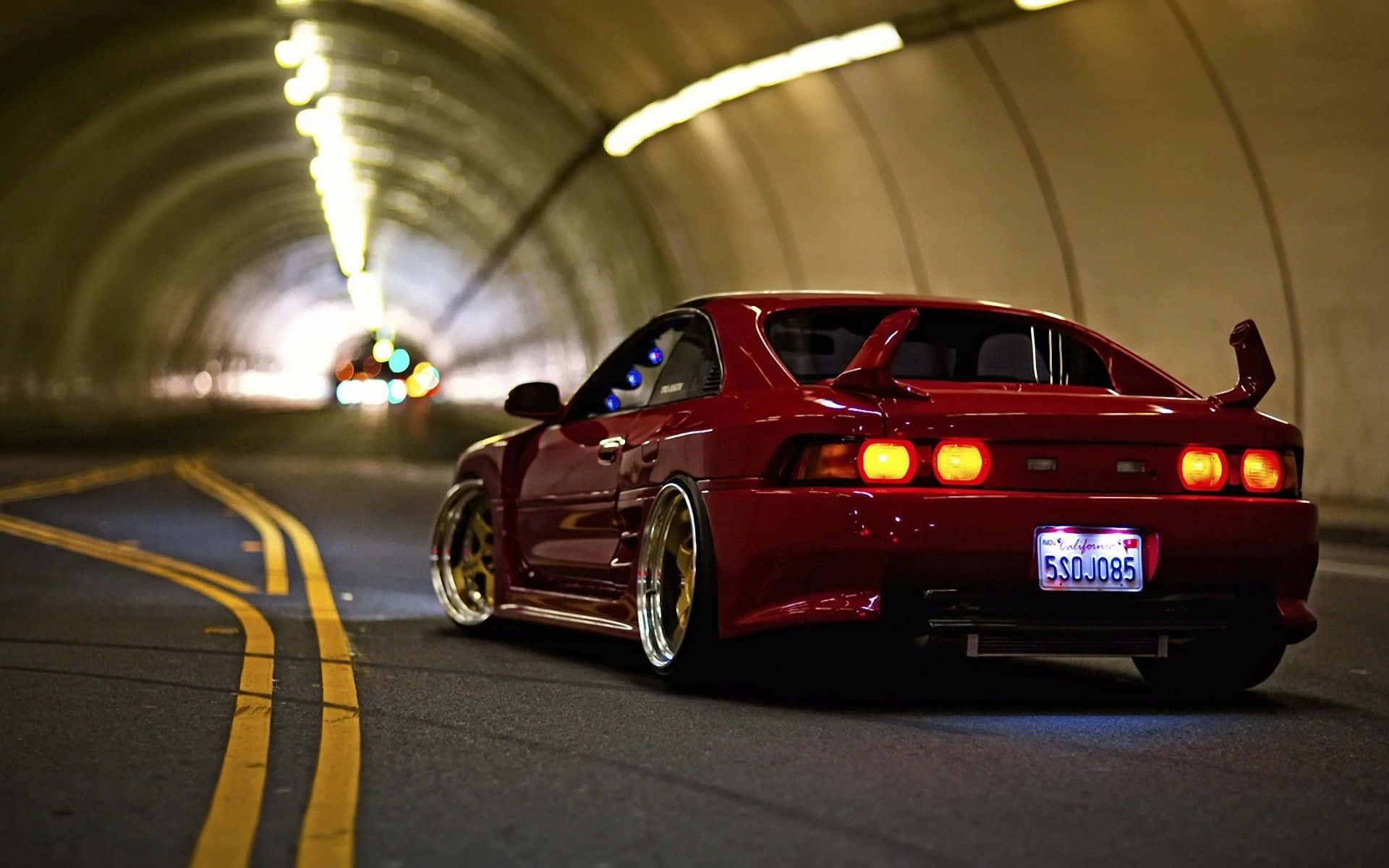 A Red Sports Car Driving Down A Tunnel Background