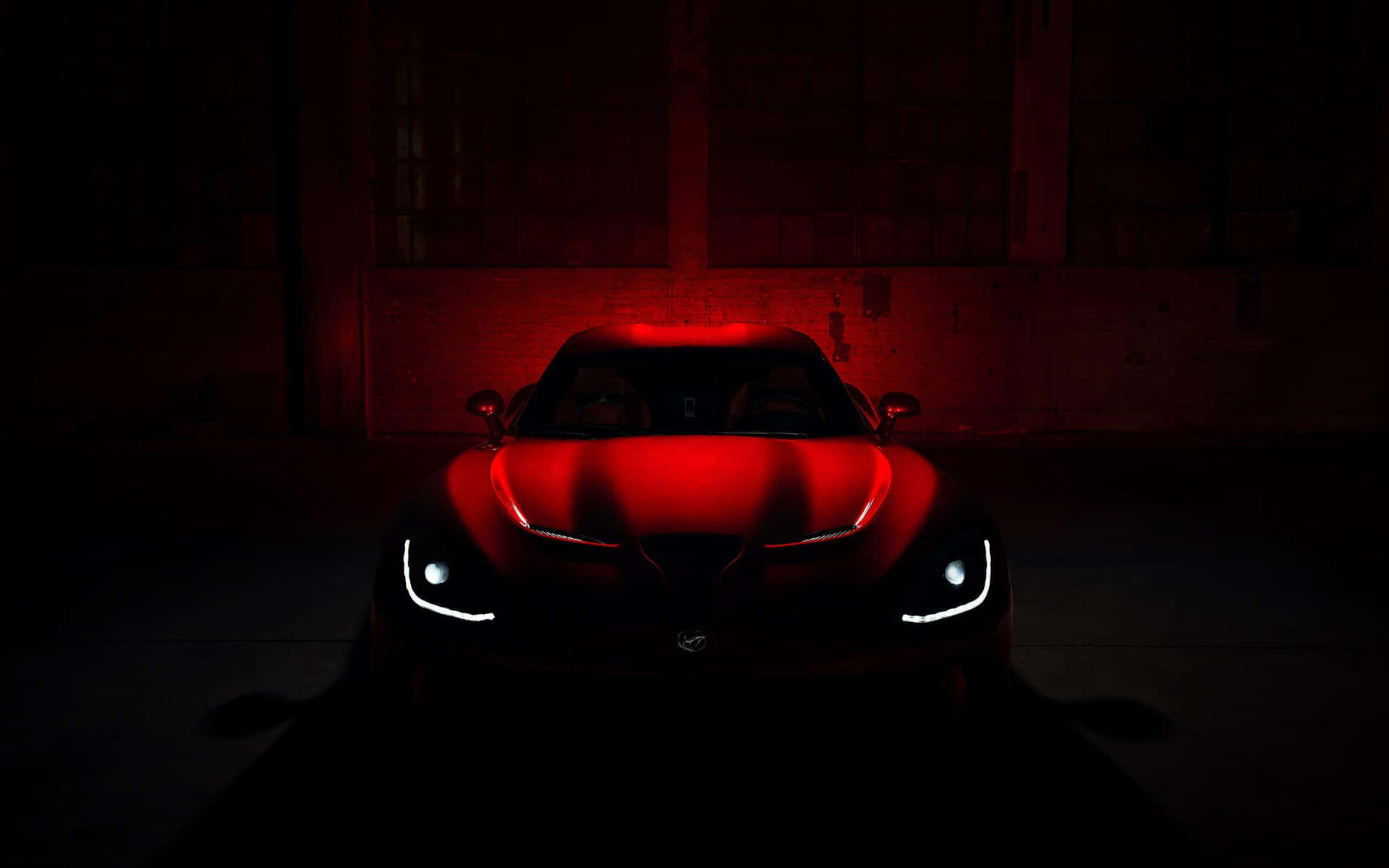 A Red Sports Car Is Lit Up In The Dark Background