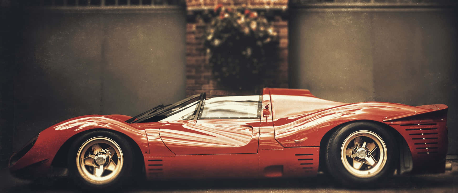 A Red Sports Car Parked In Front Of A Building Background