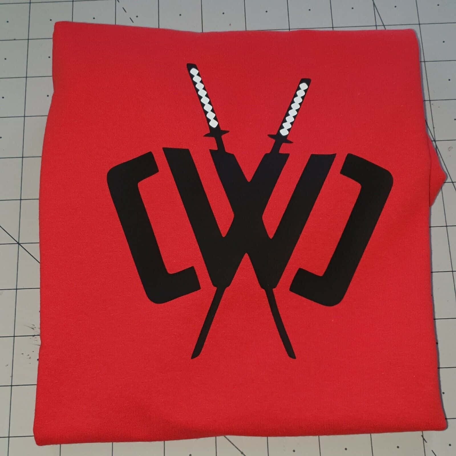 A Red Sweatshirt With Two Swords On It Background