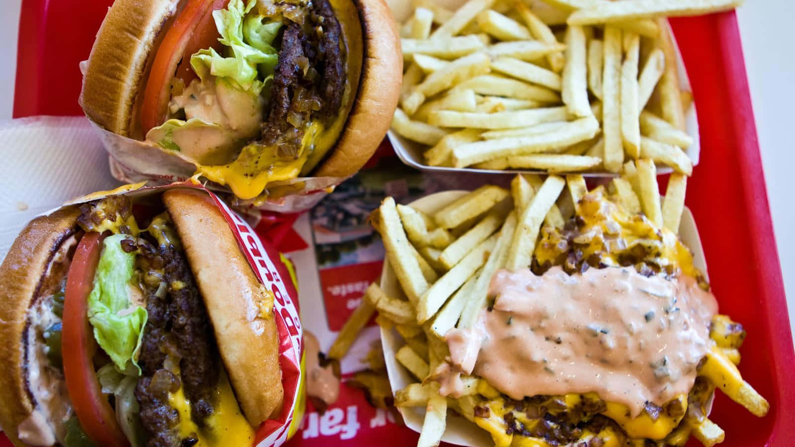 A Red Tray With Two Hamburgers And Fries Background