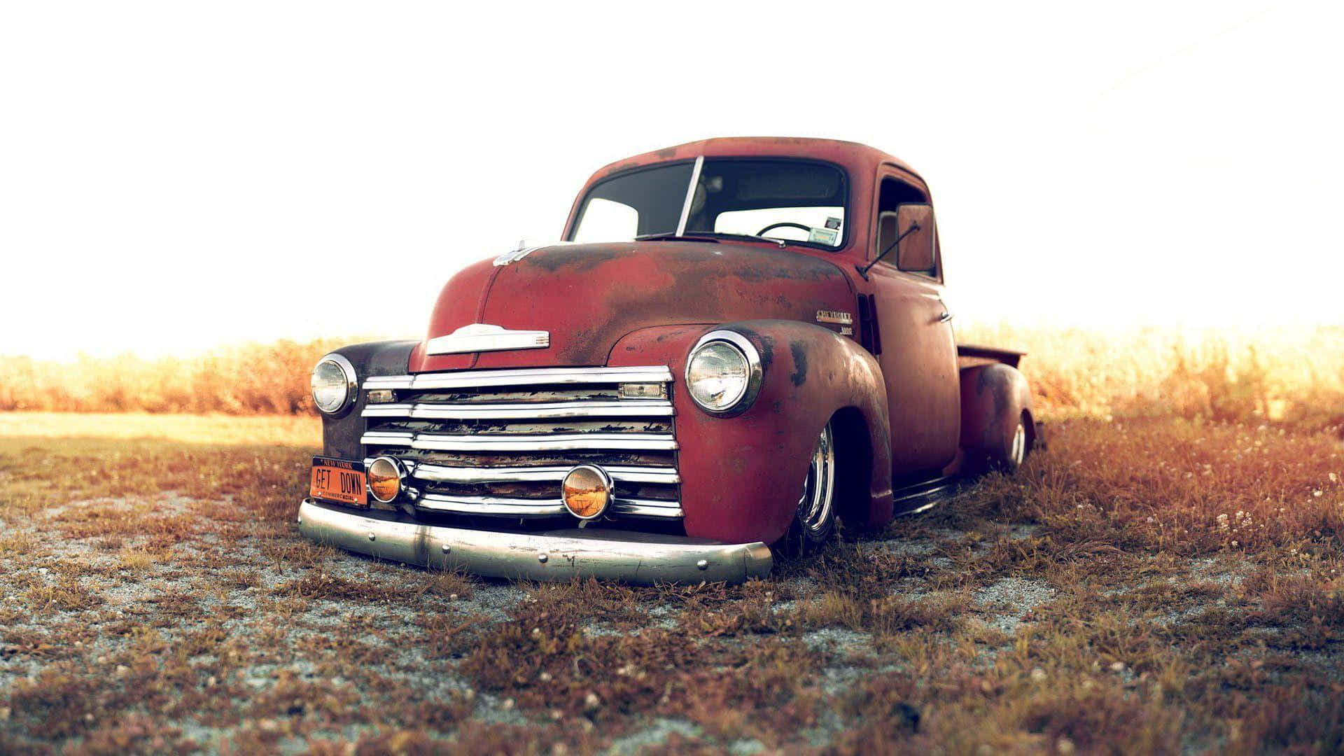 A Red Truck Is Parked In A Field Background