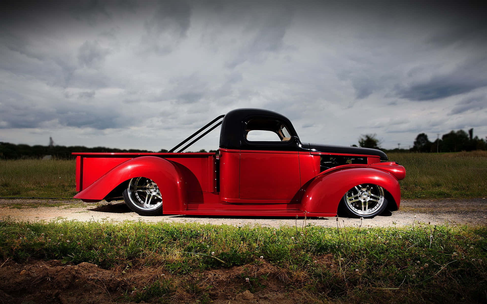 A Red Truck Parked On A Dirt Road Background