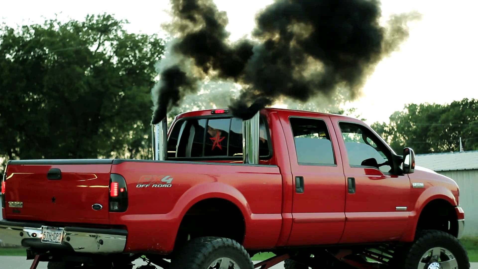 A Red Truck With Black Smoke Coming Out Of The Back Background