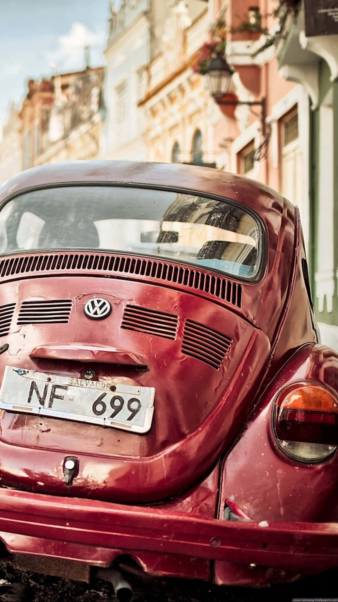 A Red Volkswagen Beetle Parked On A Street Background