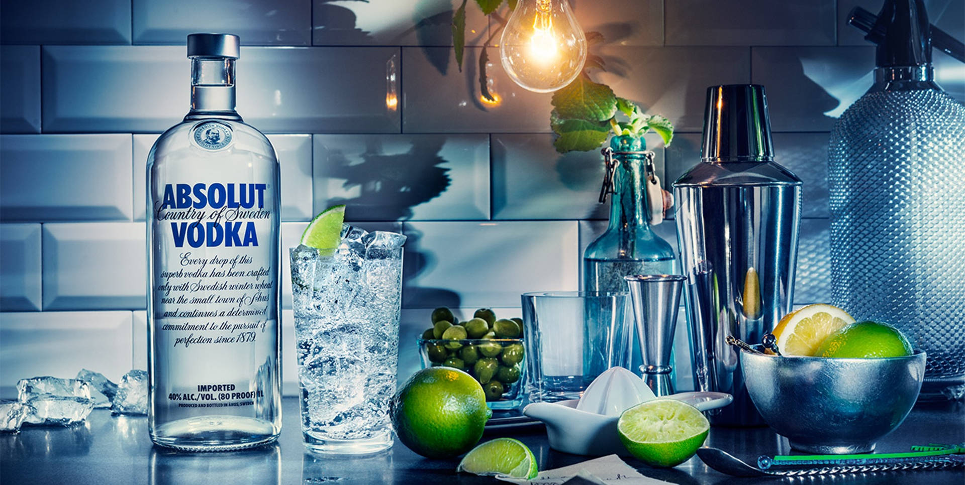 A Refreshing Scene Featuring A Bottle Of Absolut Vodka, A Lemon, And A Light Bulb.