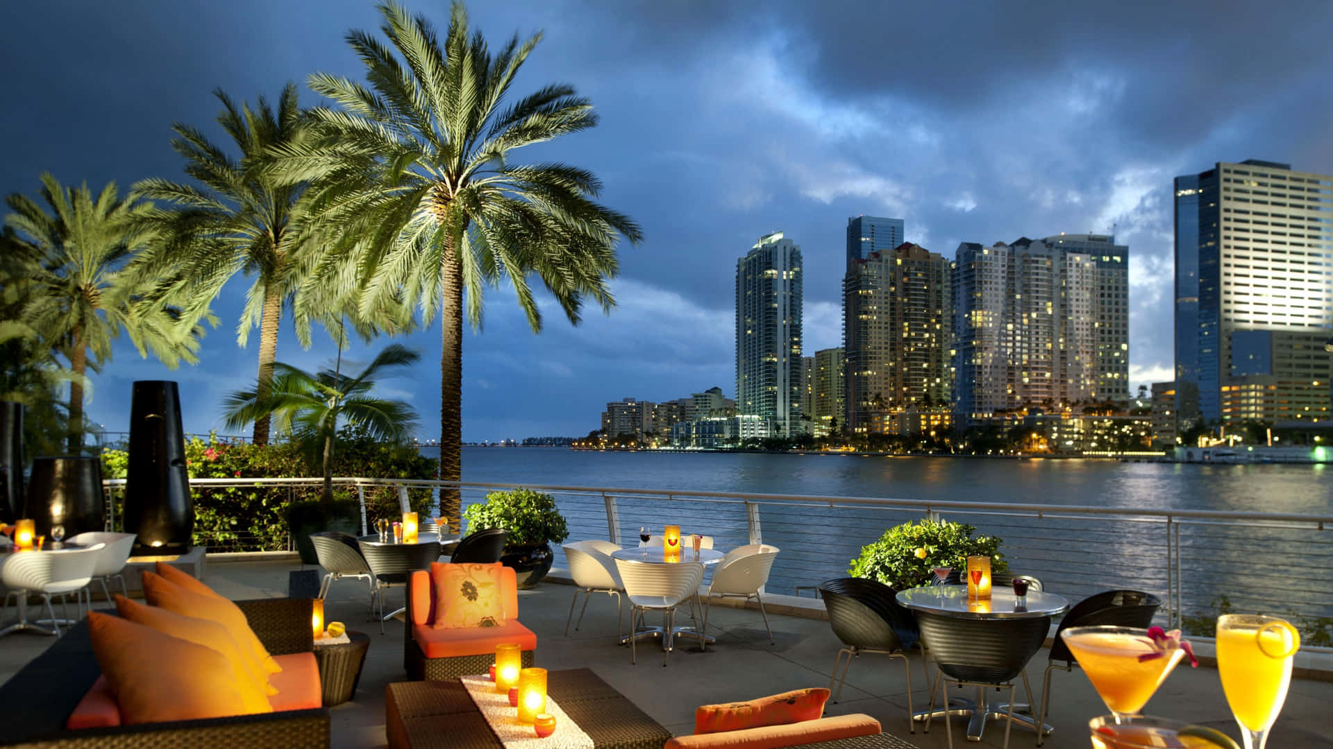 A Restaurant With Tables And Chairs Overlooking The Water Background