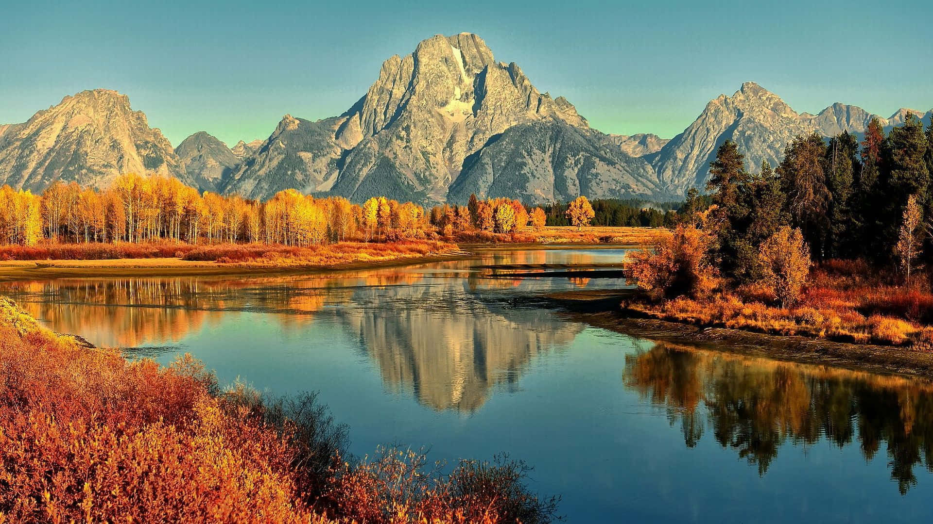 A River Surrounded By Mountains In Autumn Background