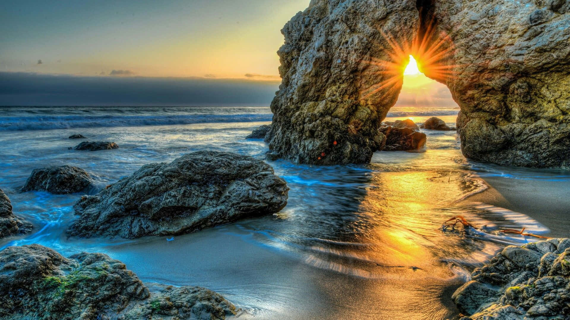 A Rock Arch In The Ocean At Sunset Background