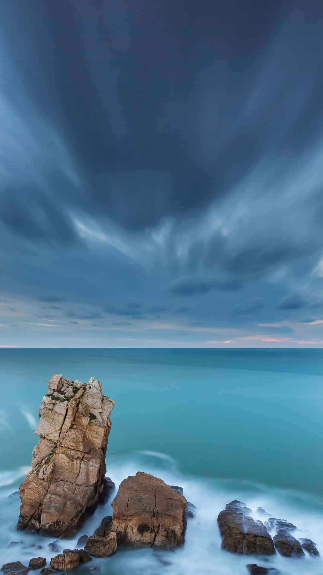 A Rock Formation With A Dark Sky And Ocean Background