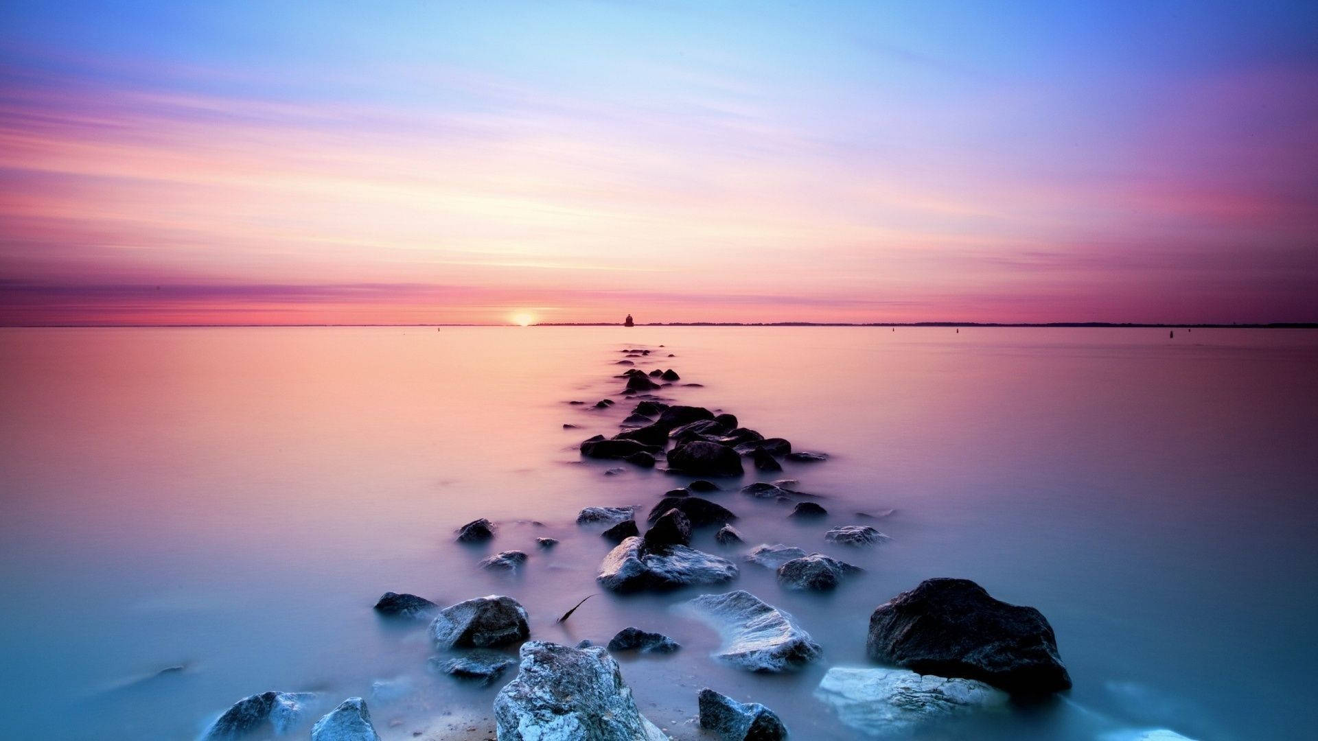 A Rock Line With A Sunset In The Background Background