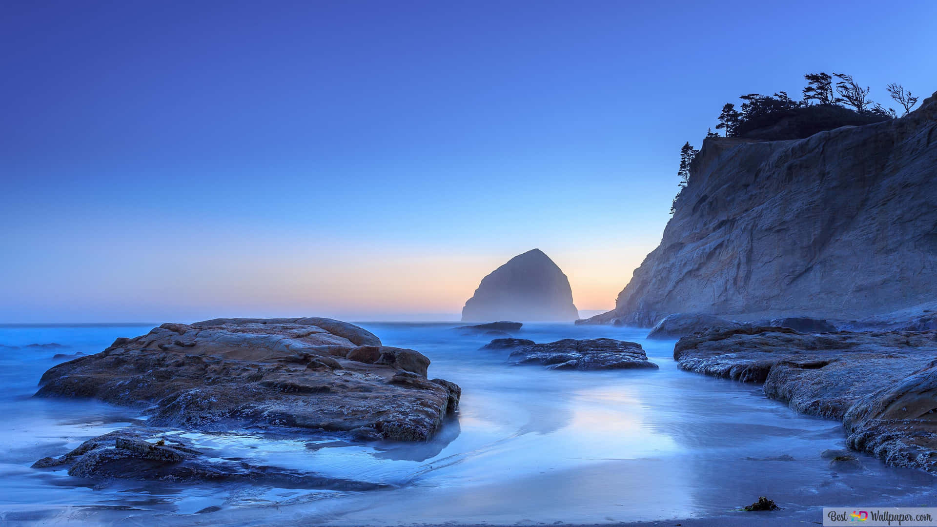 A Rocky Beach With Rocks And A Sunset Background