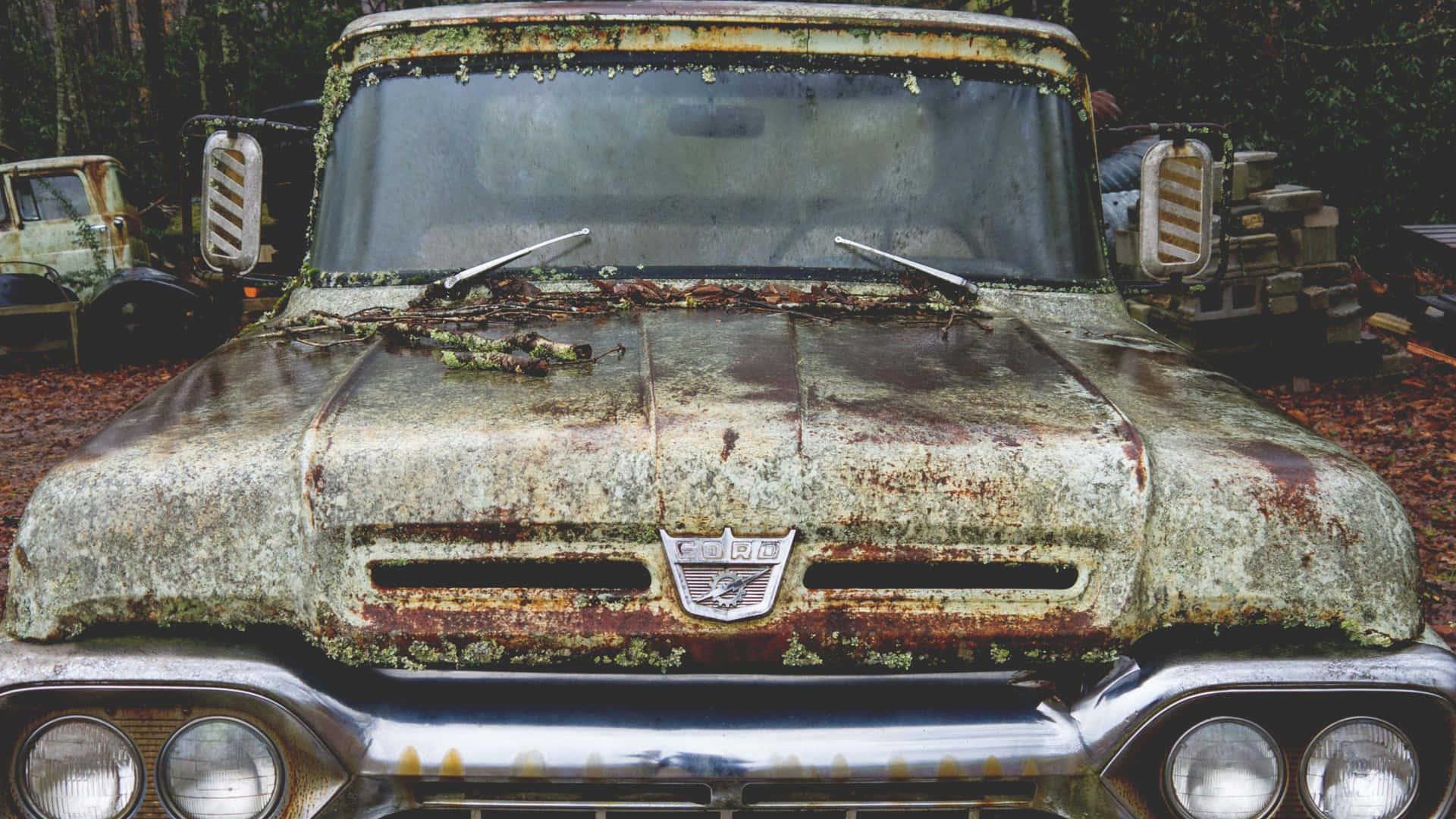 A Rusty Truck Parked In The Woods Background