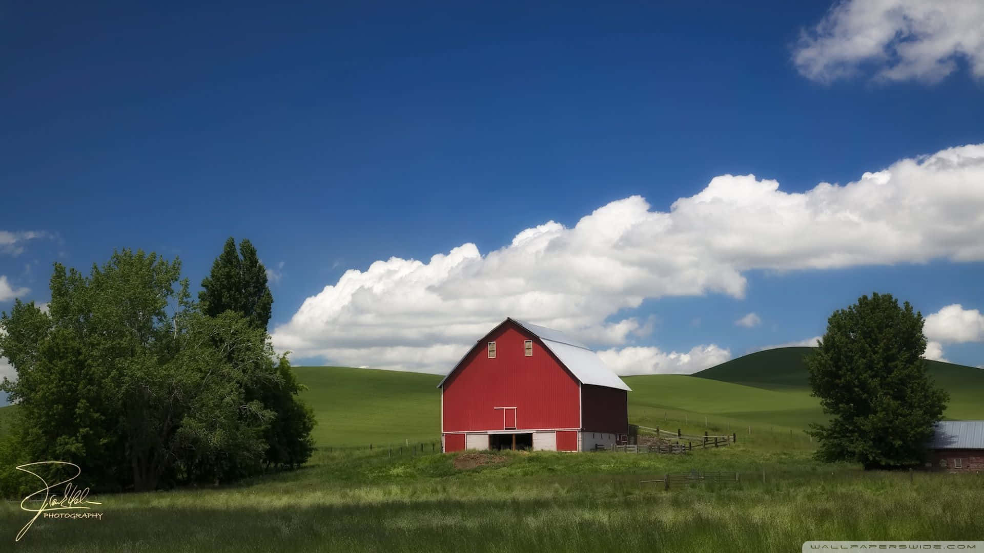 A Scenic Country Landscape Of Rolling Green Hills Complemented By The Beauty Of A Cozy Farmhouse. Background