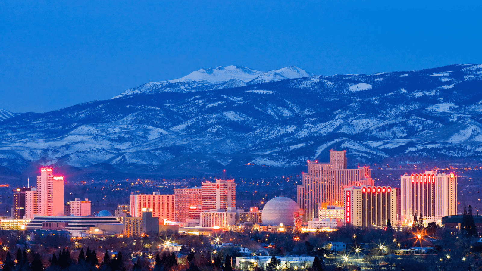 A Scenic Skyline Of Reno, Nevada, With The Sierra Nevada Range In The Backdrop