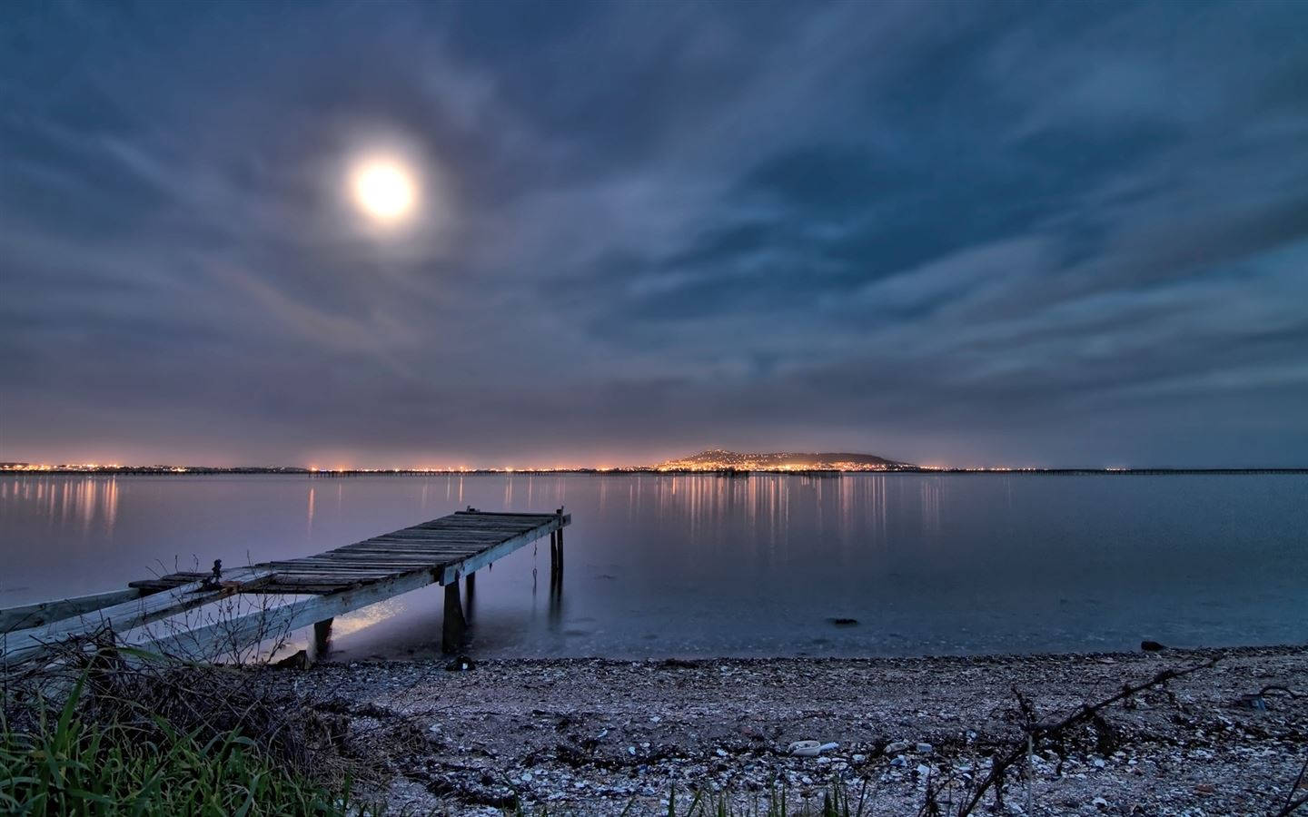 A Serene Night At The Beach Illuminated By Twinkling Lights Background